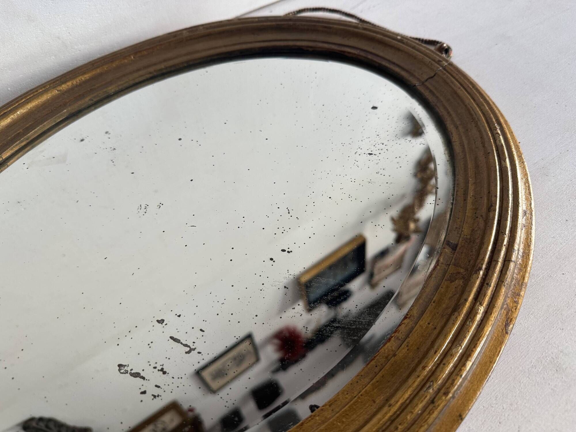 Antique oval mirror in gilded wood, bevelled mercury glass, 19th century.