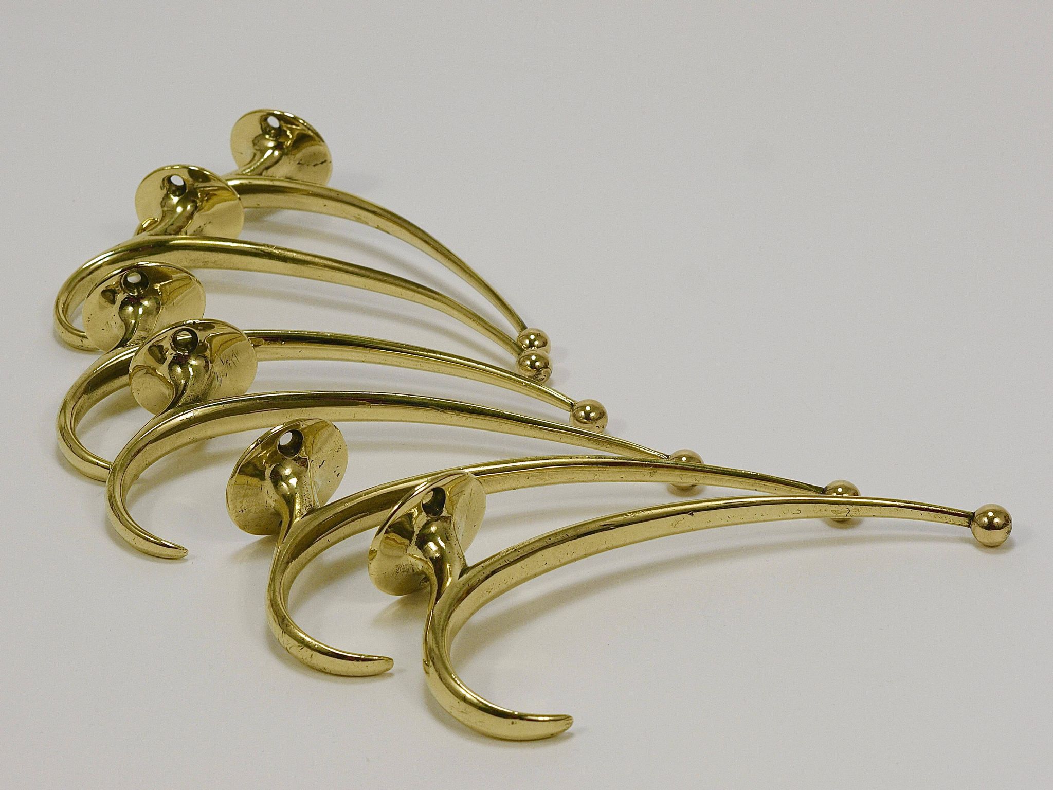 Two curved wall coat racks in brass by Franz Hagenauer, Vienna, mid-20th century, 1950s.