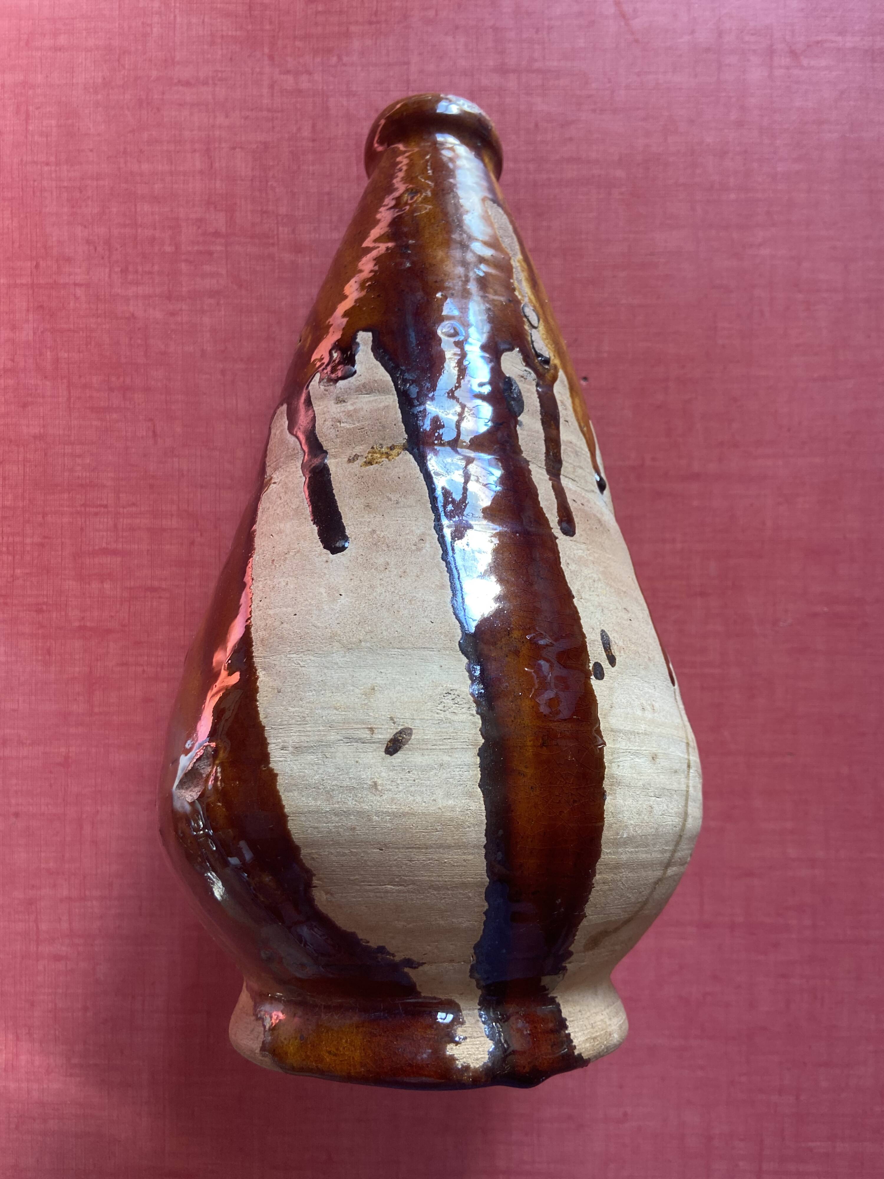 Large antique pottery bottle in glazed terracotta with drips.