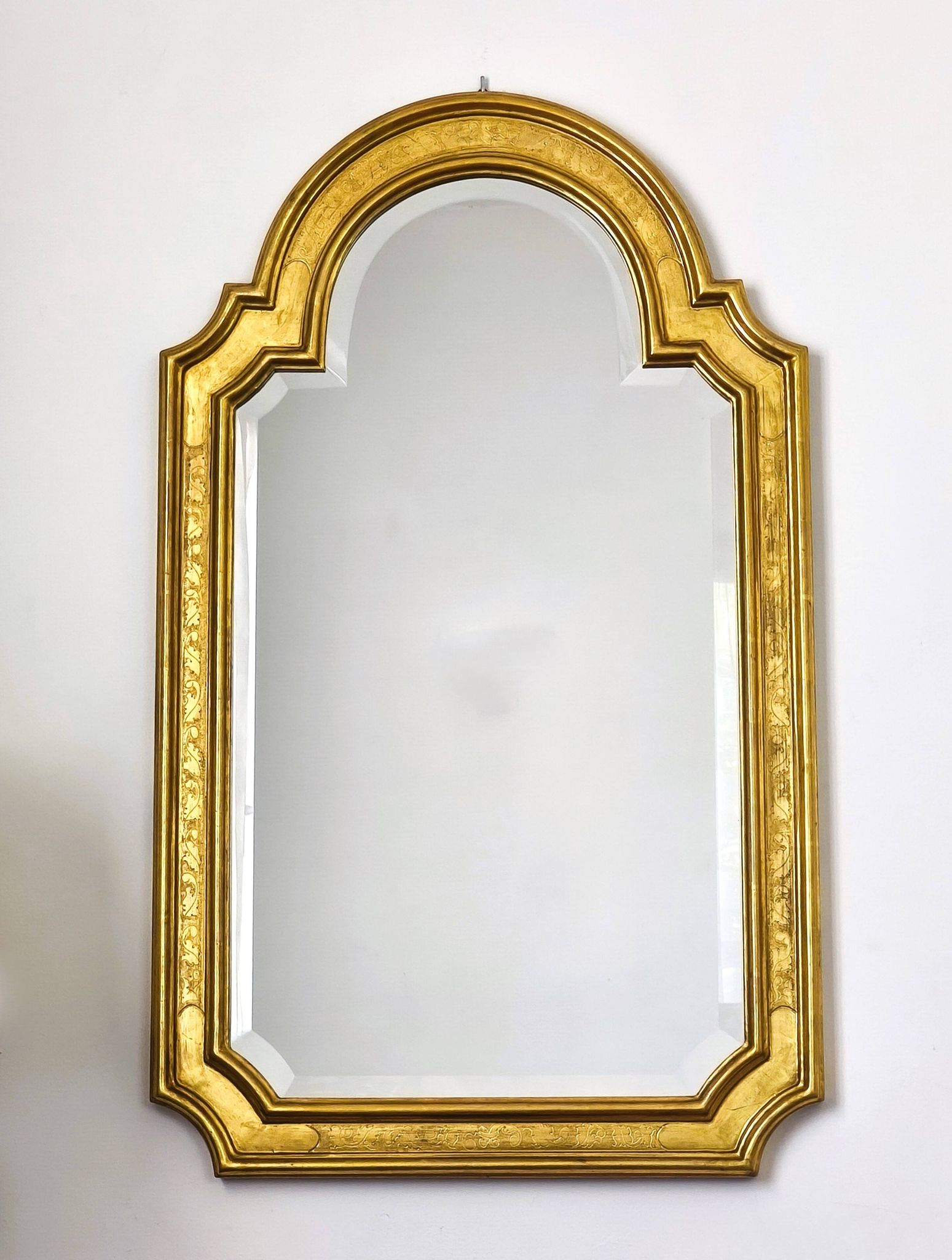 Florentine arched mirror in gilded wood with gold leaf.