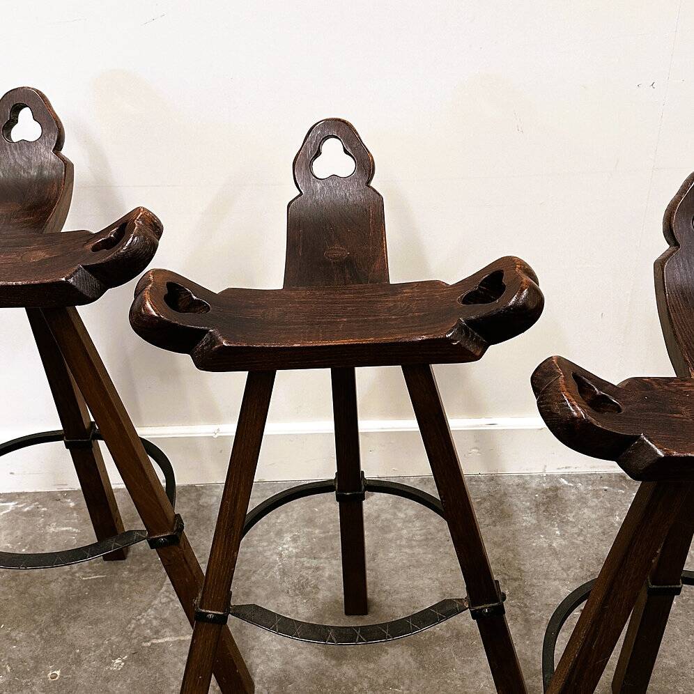 Set of 3 rustic carved oak bar stools with iron footrests, 1970s