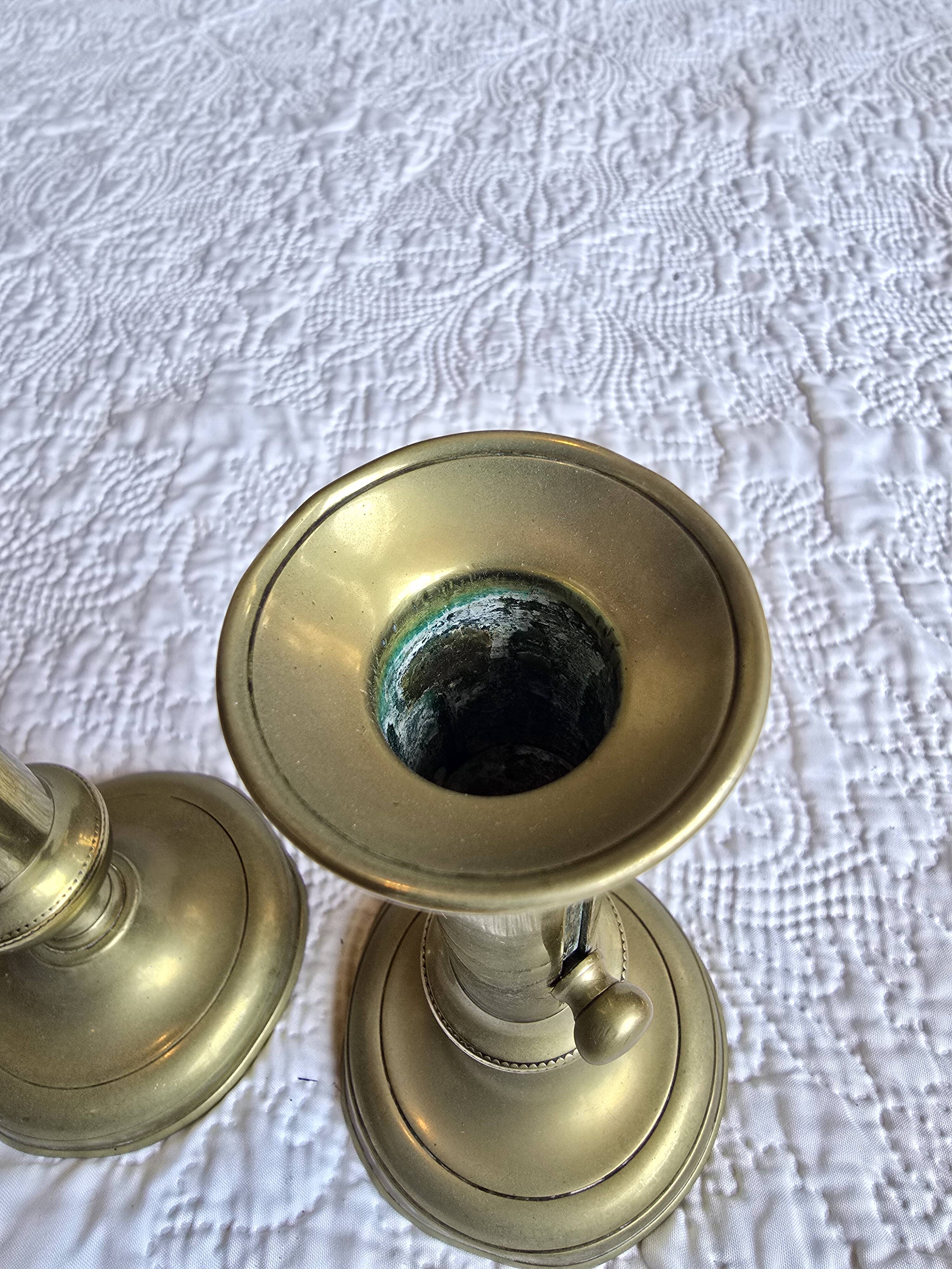 Pair of antique brass candlesticks with adjustable push mechanism from the 19th century.