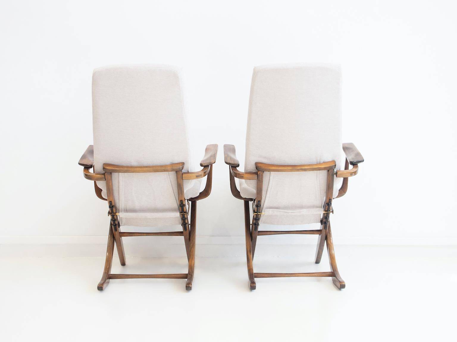 Pair of varnished wooden reclining armchairs, upholstered in lightweight fabric.