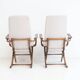 Pair of varnished wooden reclining armchairs, upholstered in lightweight fabric.