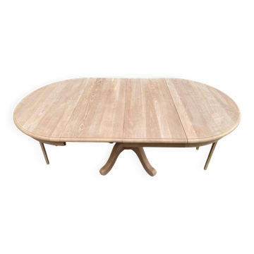 Round extendable dining table stripped in raw solid cherry wood with a central leg.