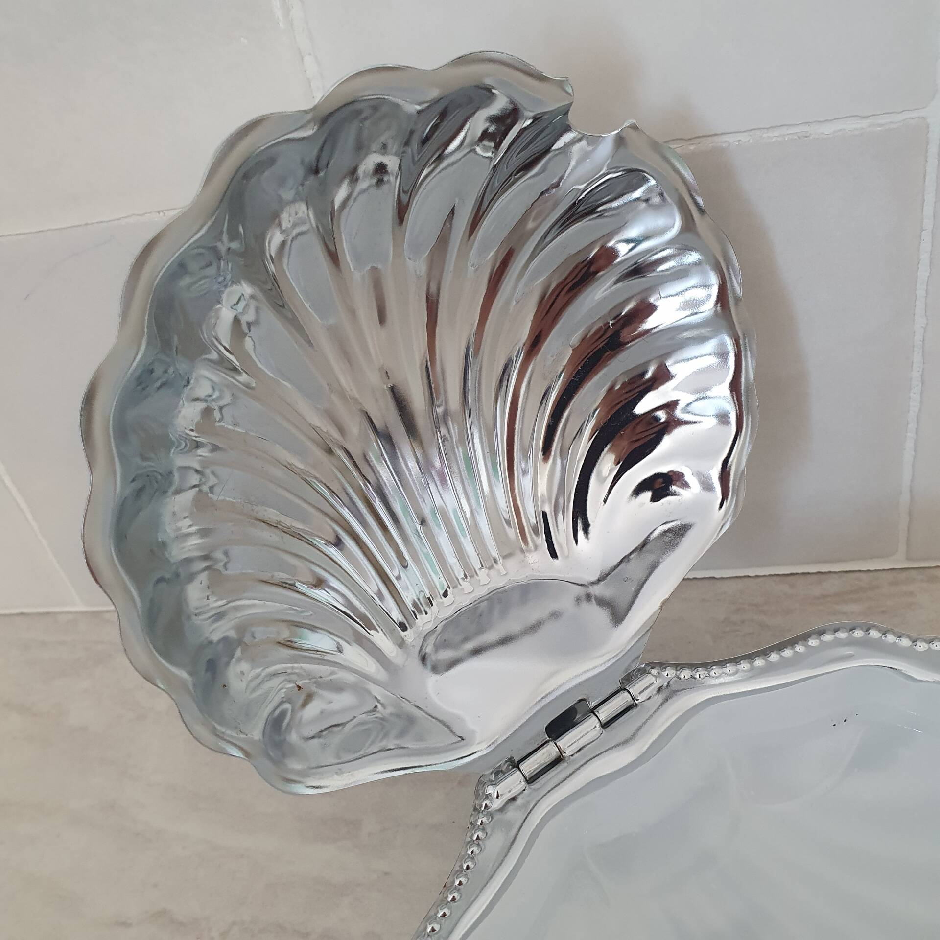 Scallop shell butter dish in stainless steel with its white glass saucer.