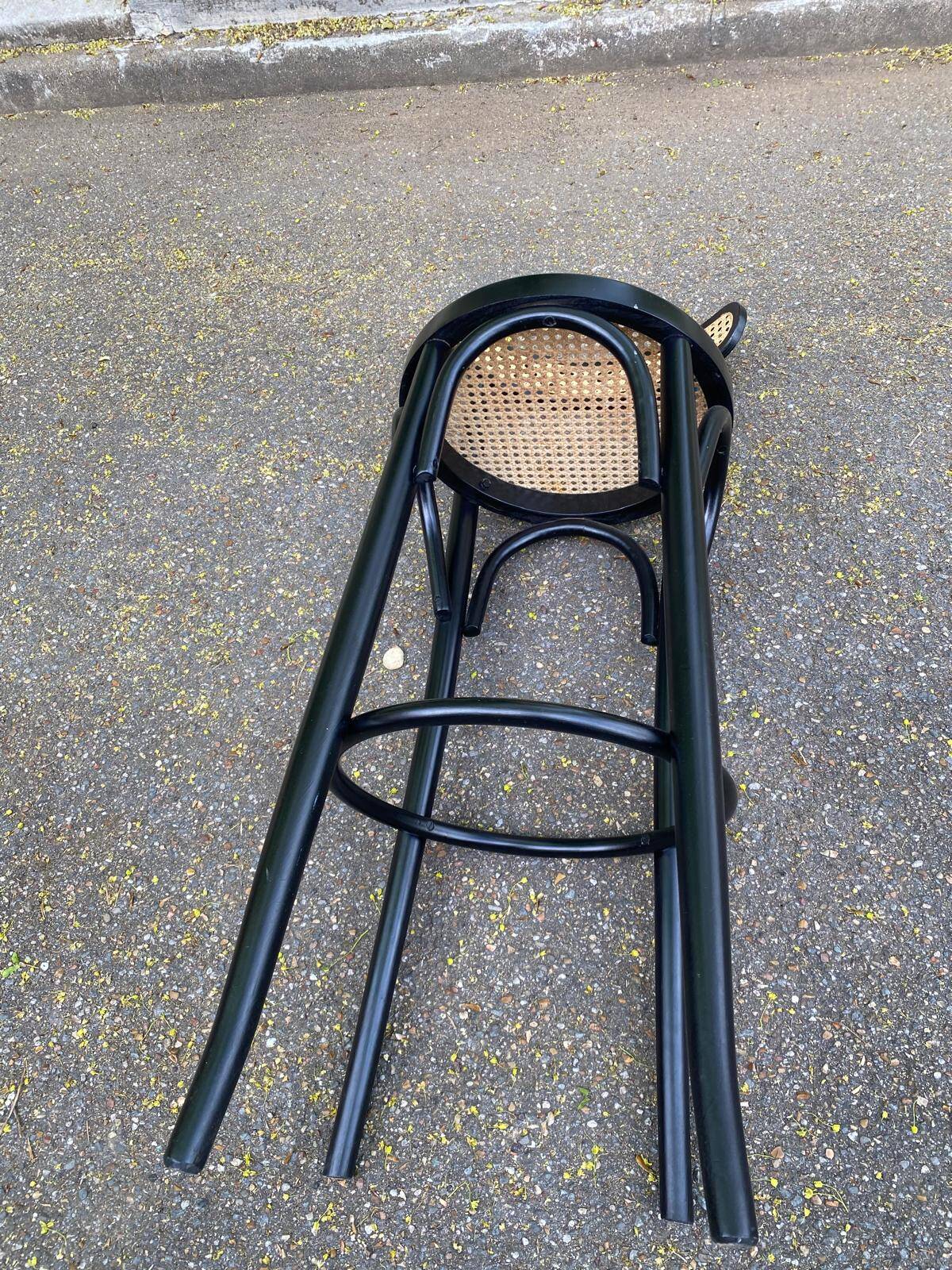 High bistro bar stool in curved black wood with a cane backrest.