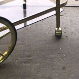 Two-tier bar cart in gold-plated brass with transparent glass shelves, yellow finish.