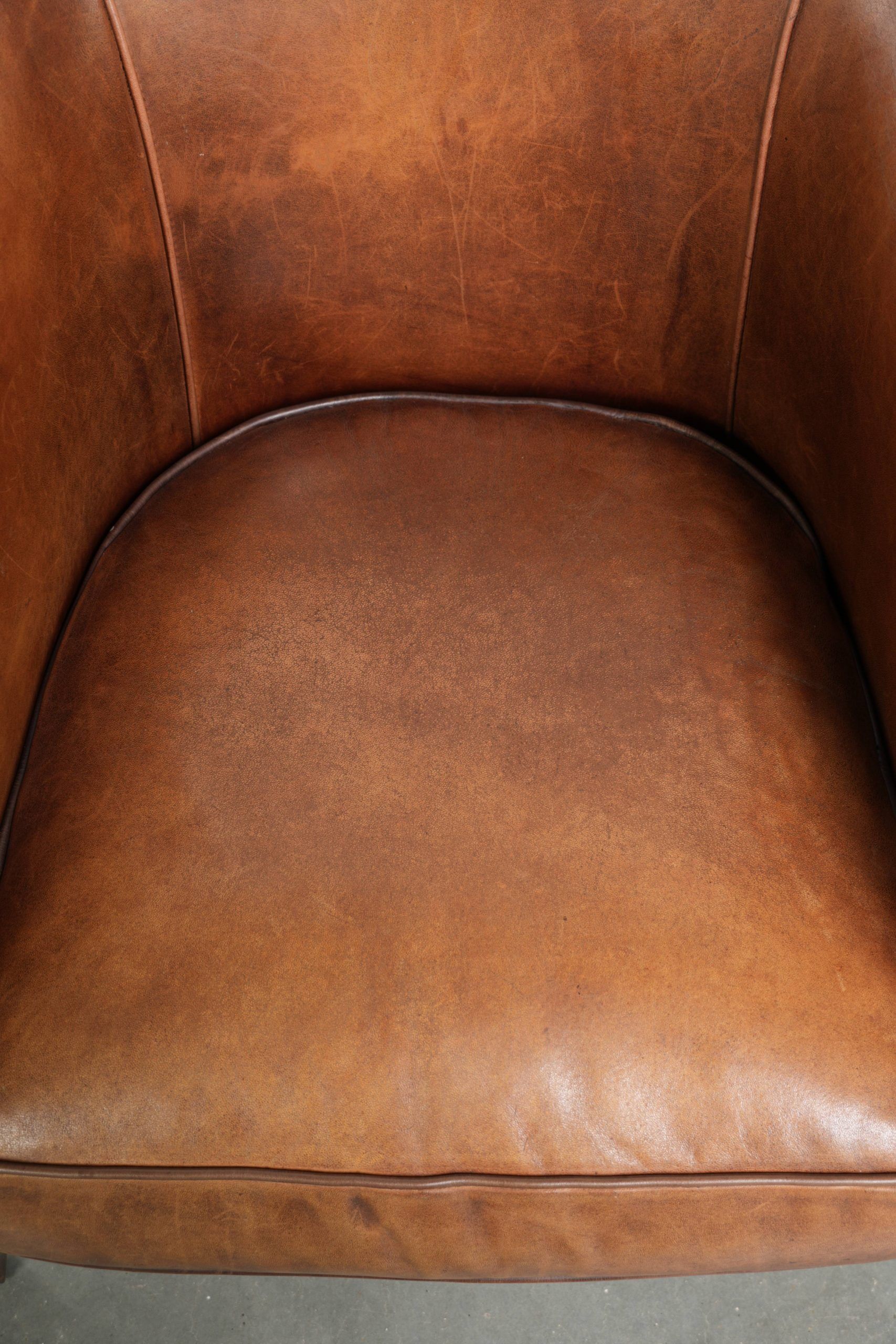 Sheepskin club armchair with a cognac colour finished with decorative nails