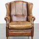 Cognac-colored sheep leather wingback chair finished with black piping