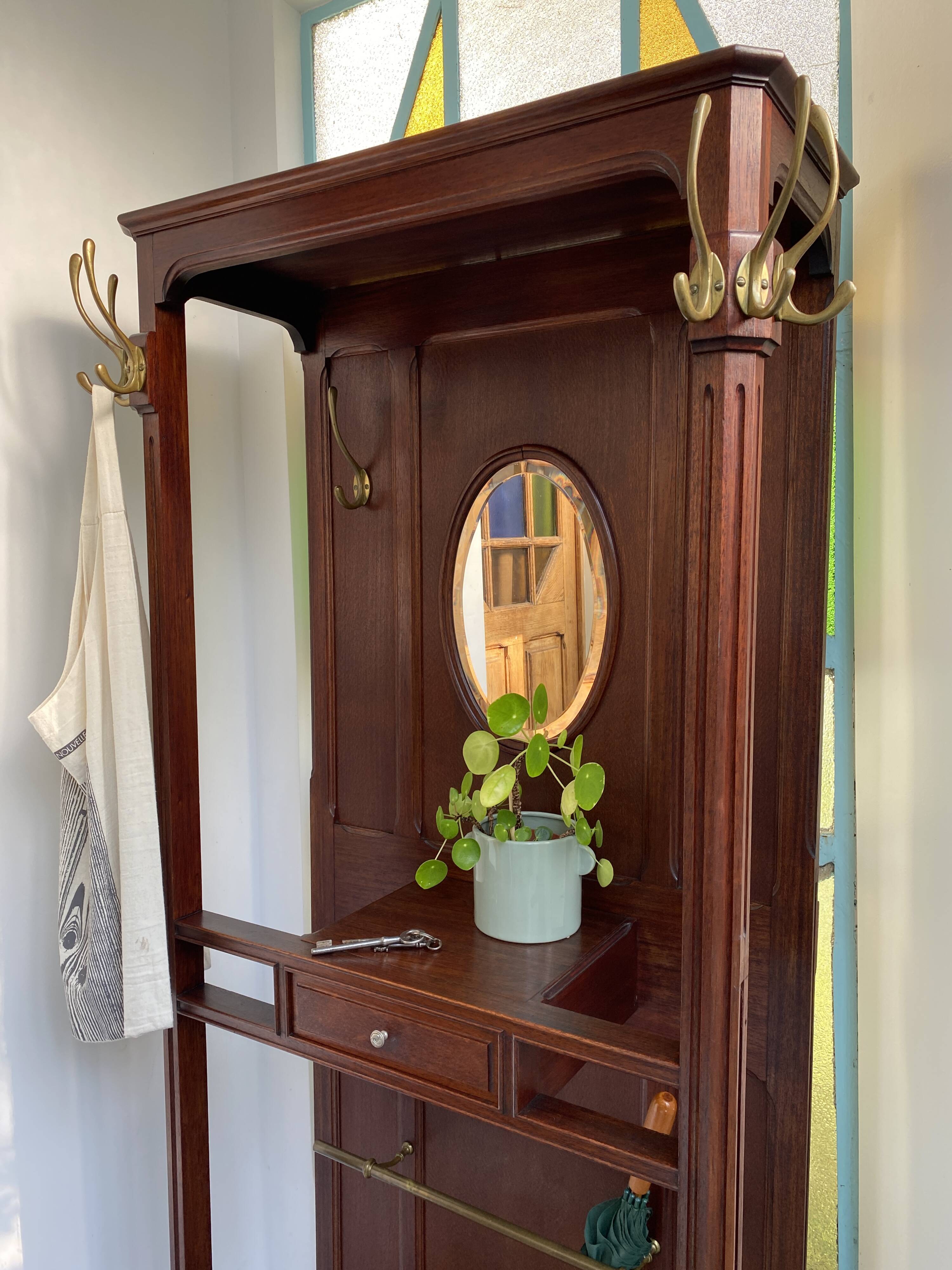 Antique wooden coat rack with mirror and shelf.
