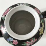 Vintage Chinese teapot with floral polychrome decoration on a black background.