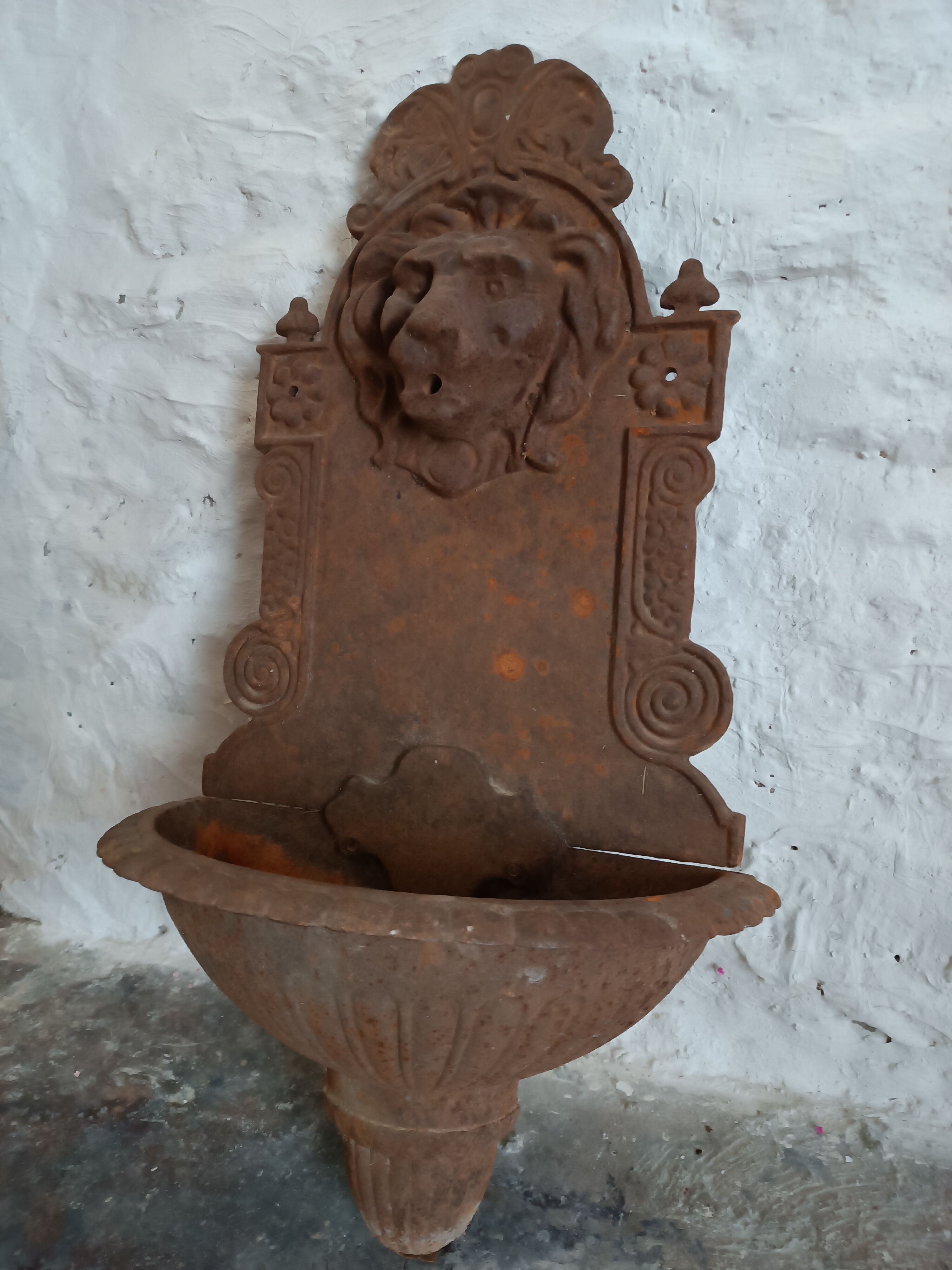 Old cast iron wall fountain with lion's head