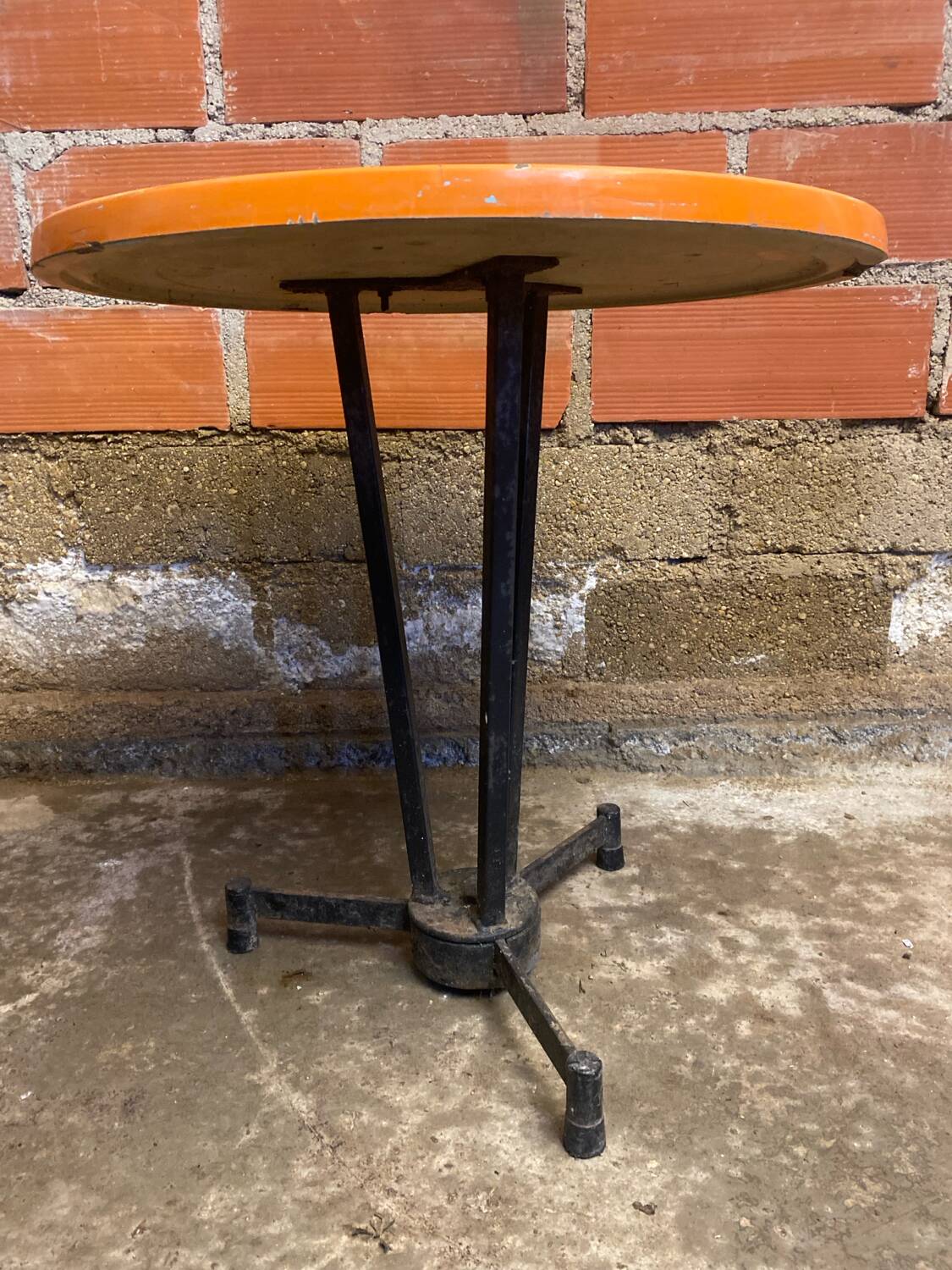 Vintage bistro table with black cast iron base and orange bakelite top, 1950s