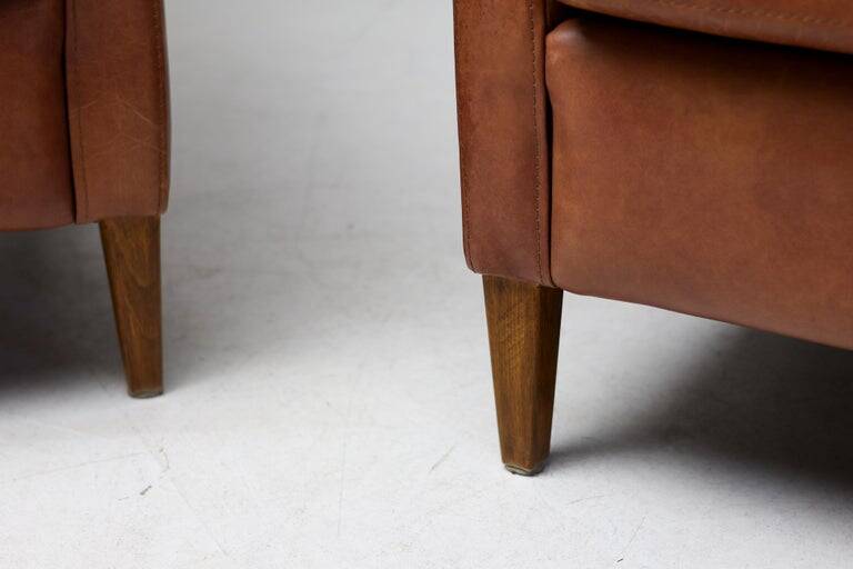Pair of Art Deco armchairs in brown leather and teak, Netherlands, 1970s.