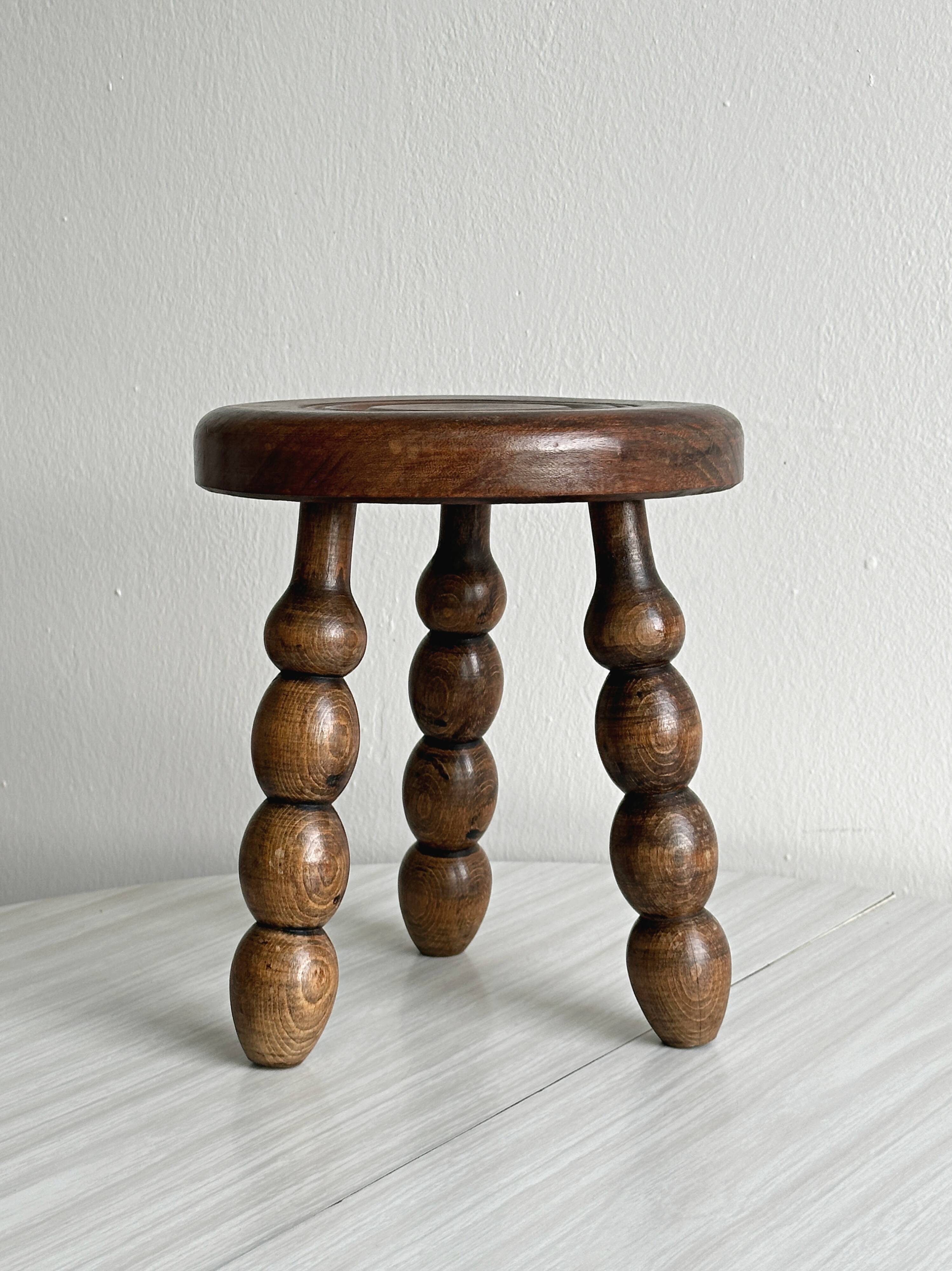 Small three-legged stool made of turned wood.