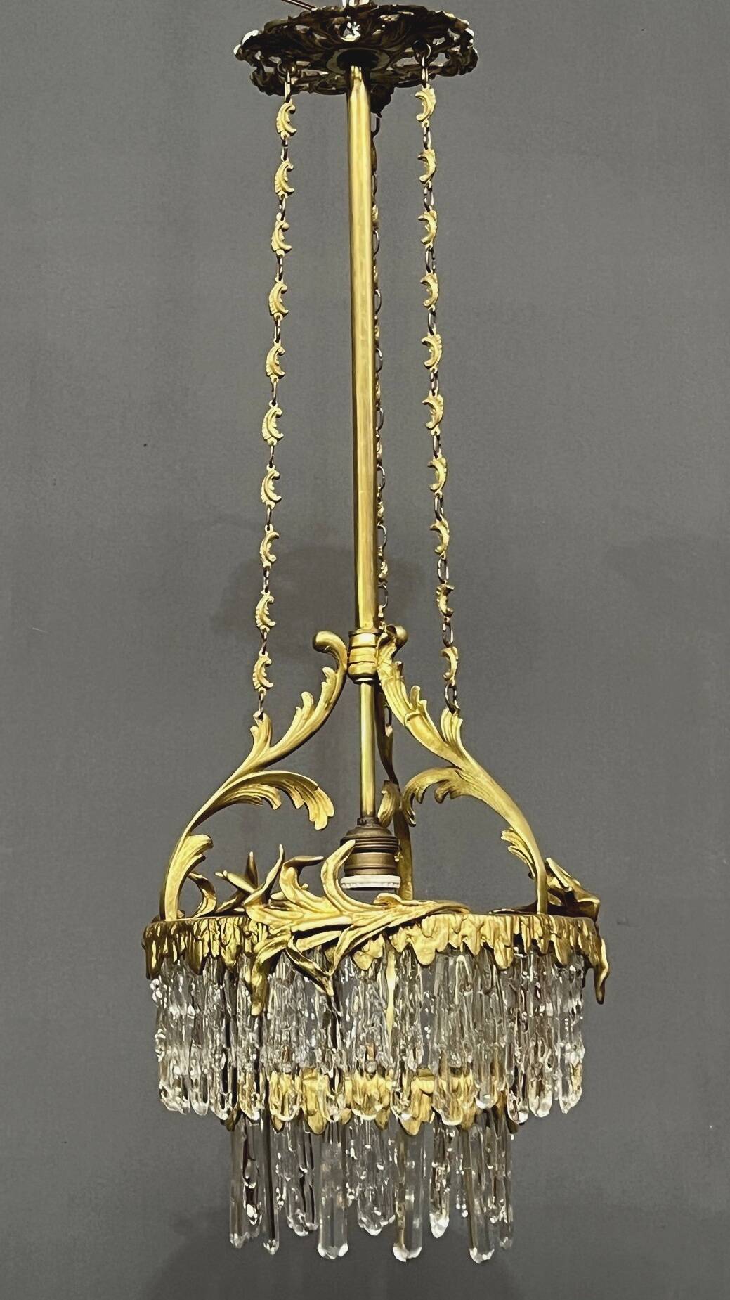 Antique chandelier in gilded bronze with crystal pendants.