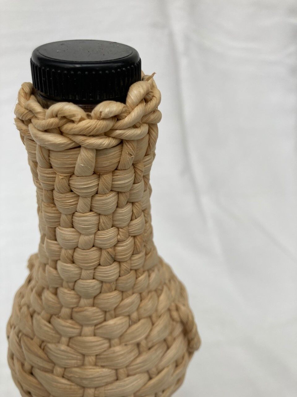 Bottle surrounded by wicker or raffia