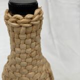 Bottle surrounded by wicker or raffia