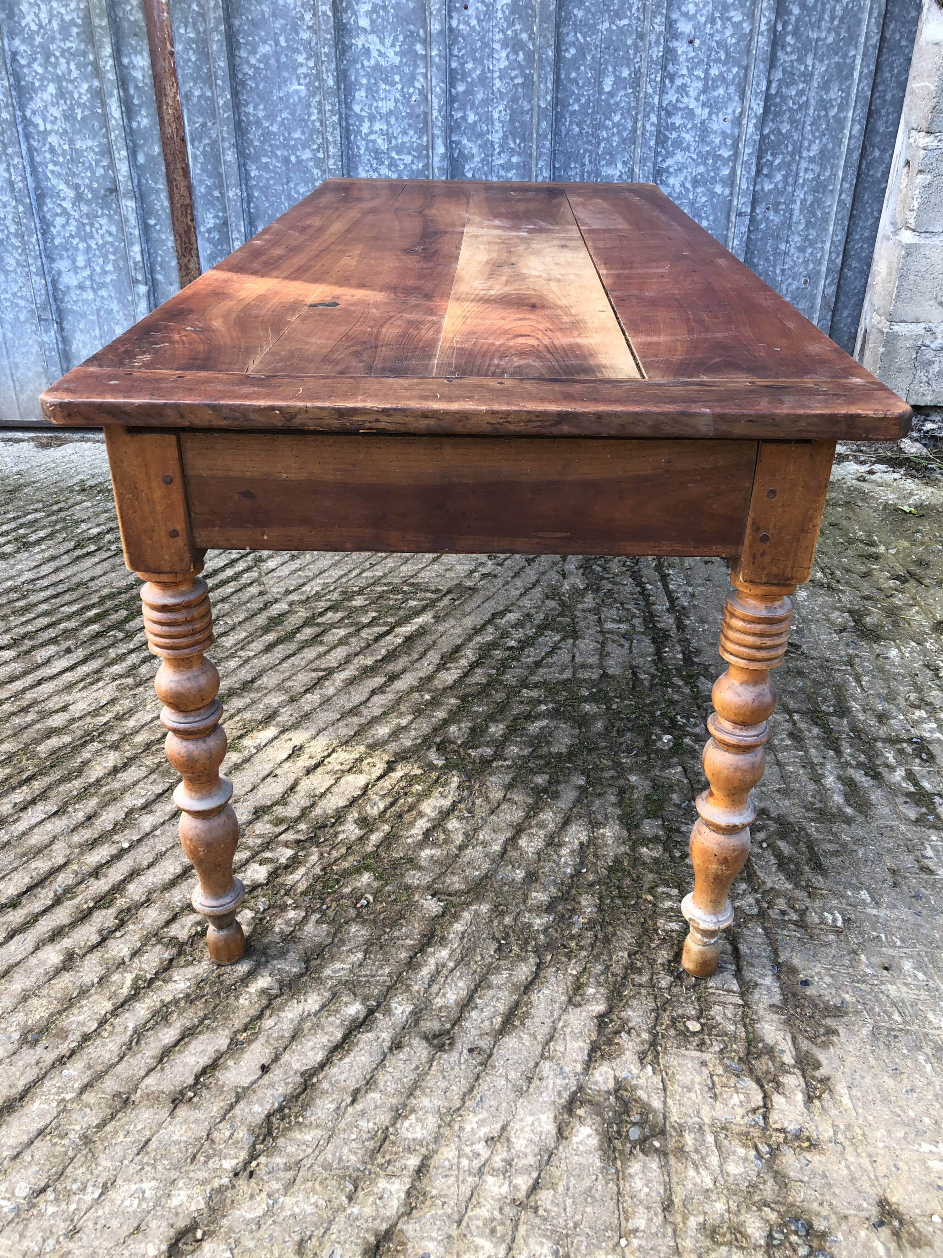 Antique farmhouse table in solid cherry wood with turned legs.