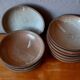Set of 10 turned stoneware plates, pyritised and glazed, wabi-sabi brutalist.