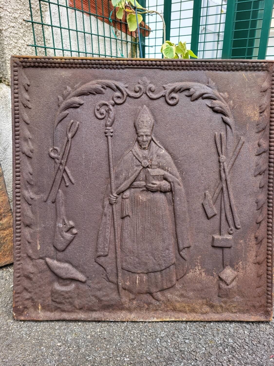 19th century cast iron fireback: bishop blessing the blacksmith's tools