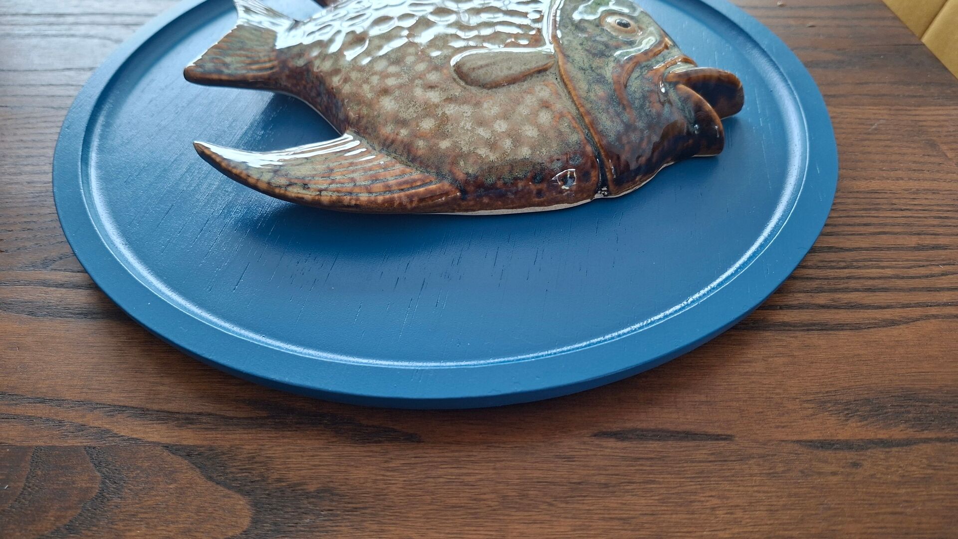 Vallauris ceramic wall sculpture of a relief fish on a blue plaque.