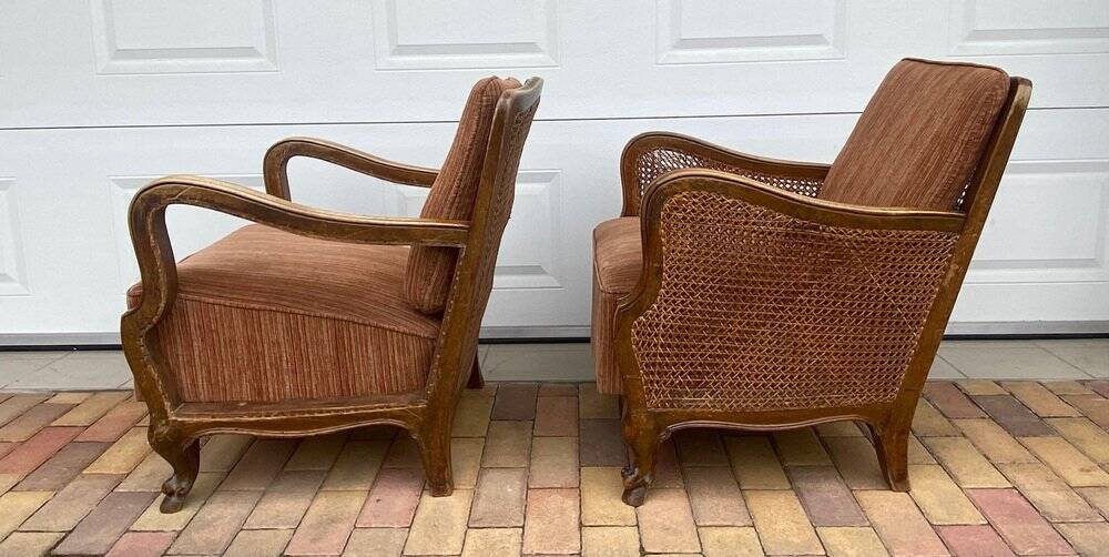 Pair of 1920s brown armchairs in carved wood and fabric, with caning detail.