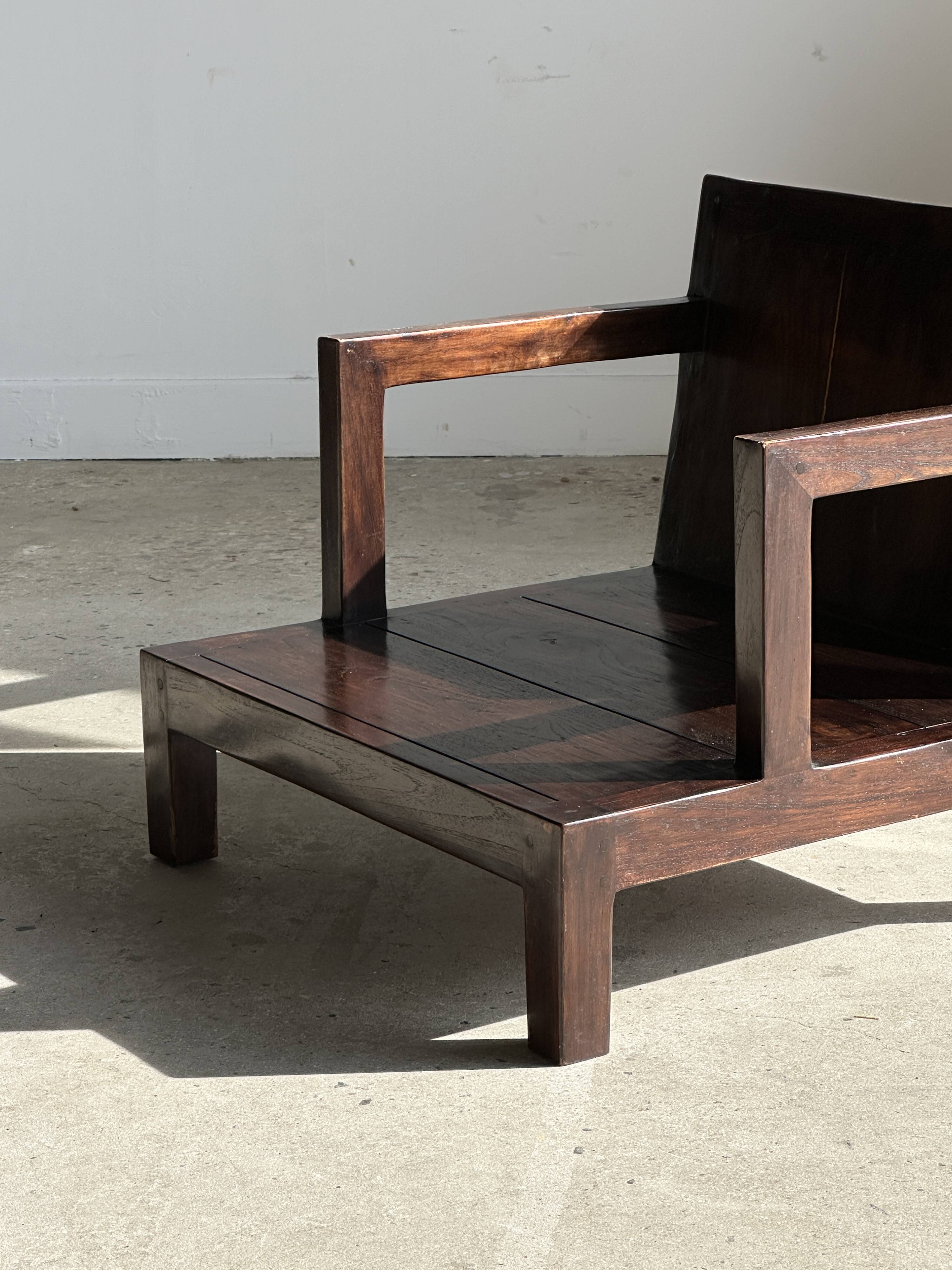 Small low armchair in varnished brown wood