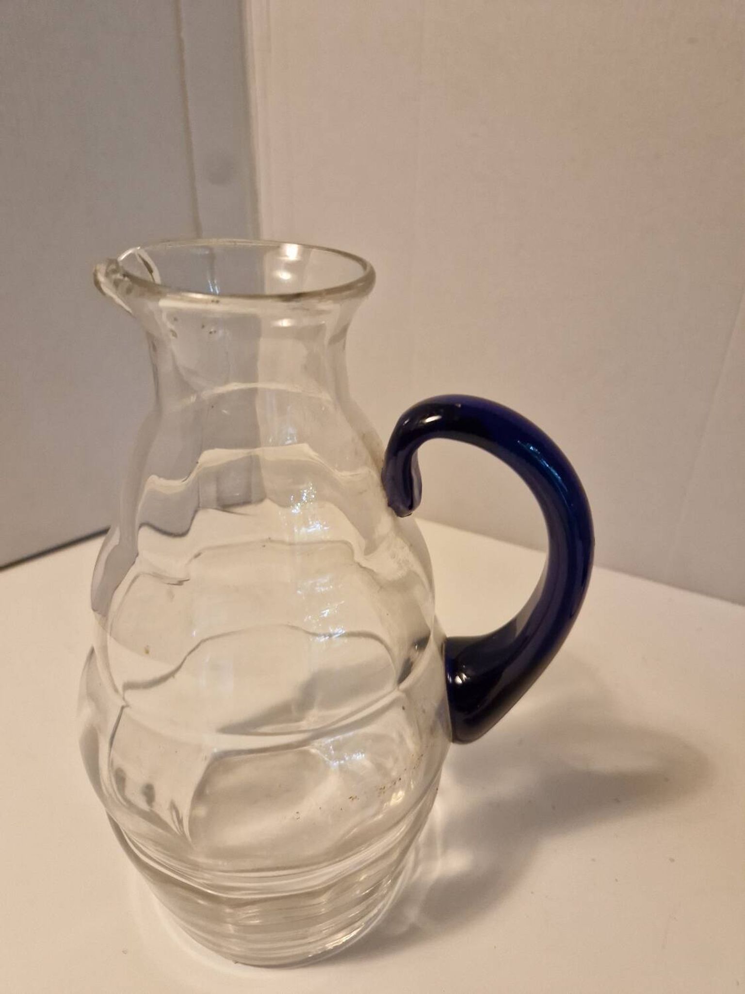 Glass carafe with wavy body and blue handle