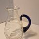 Glass carafe with wavy body and blue handle