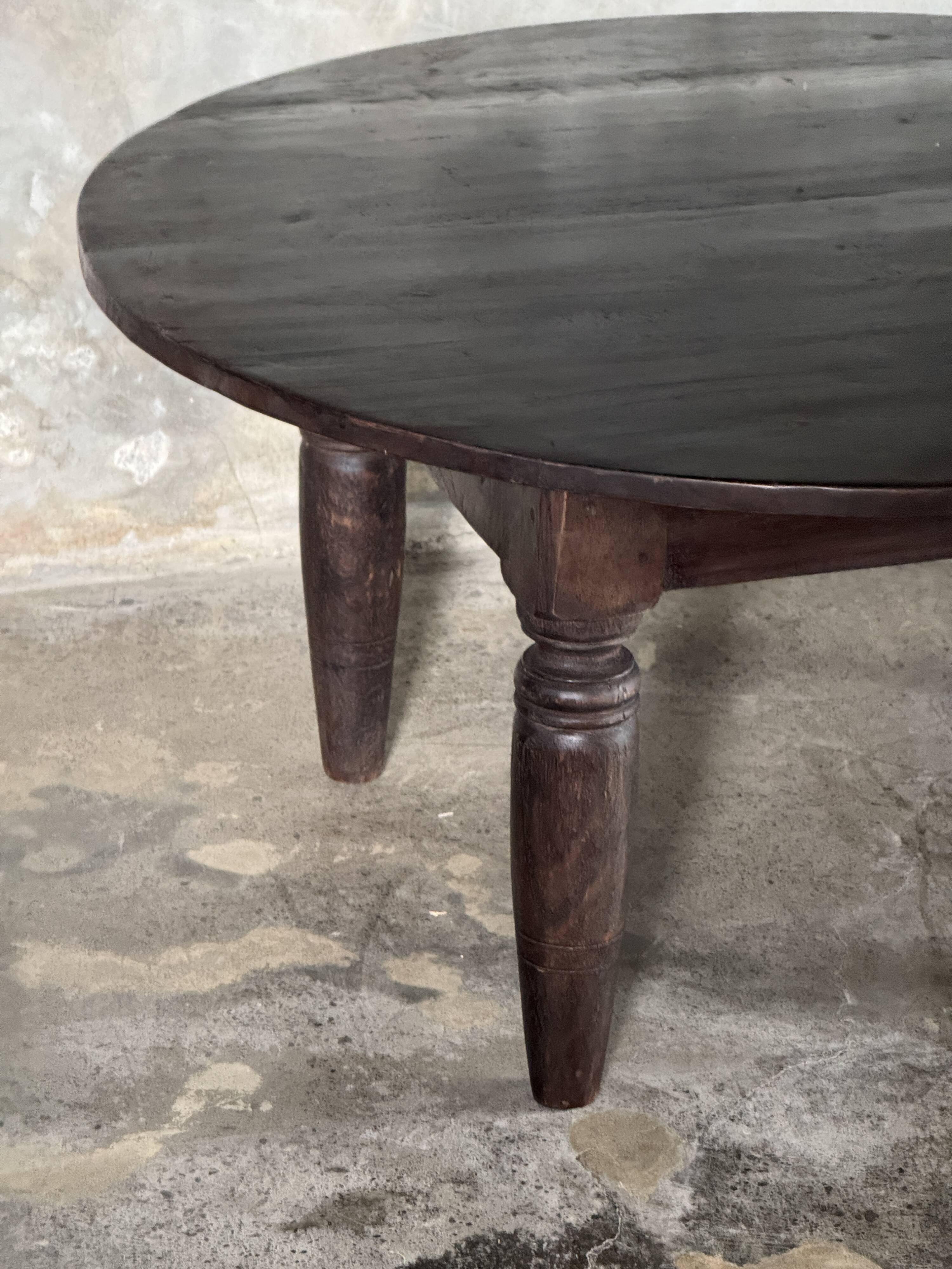Antique round coffee table in Indonesian teak with turned legs.