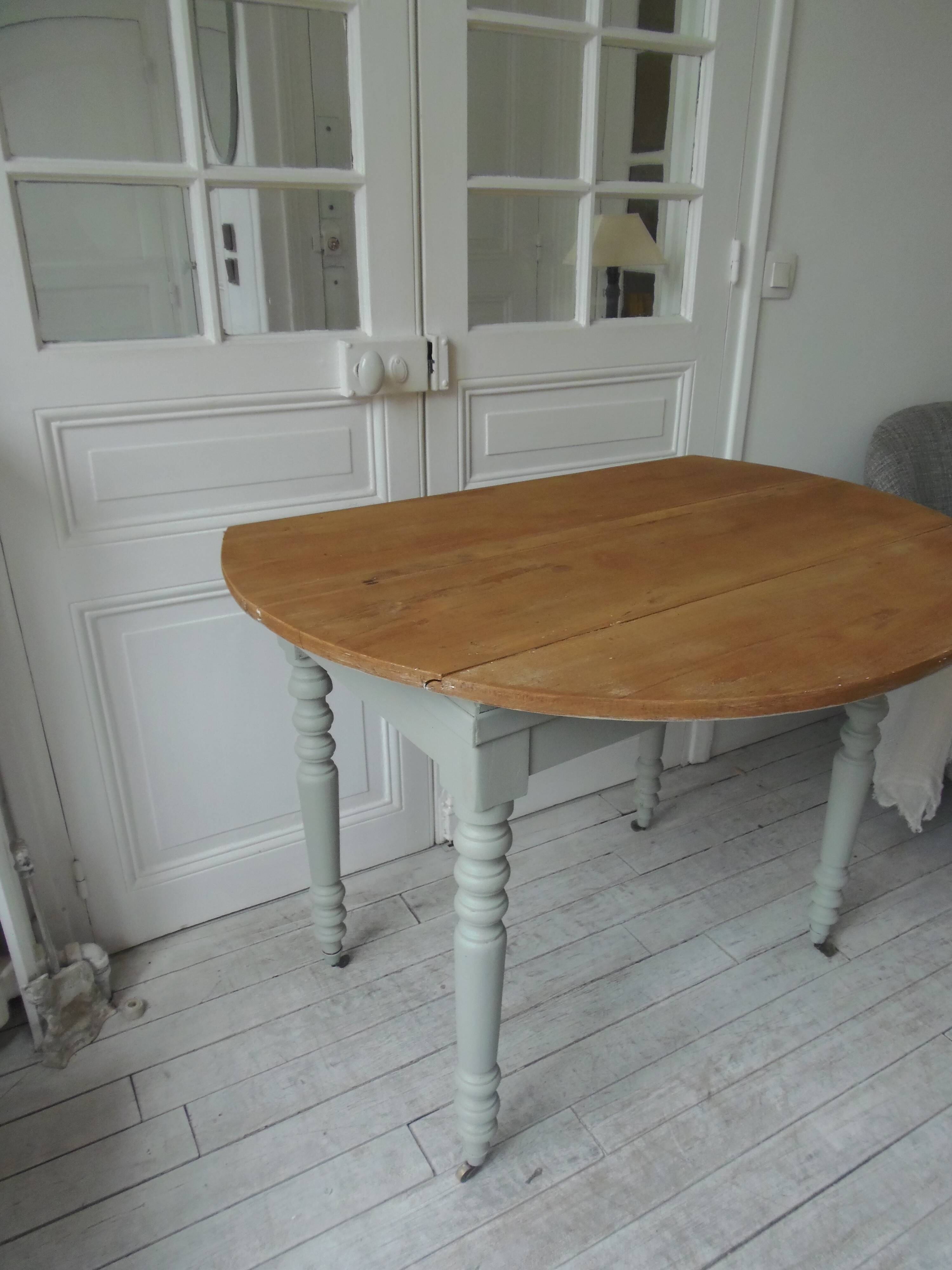 Raised walnut table with drop-leaf top, base on verdigris castors.