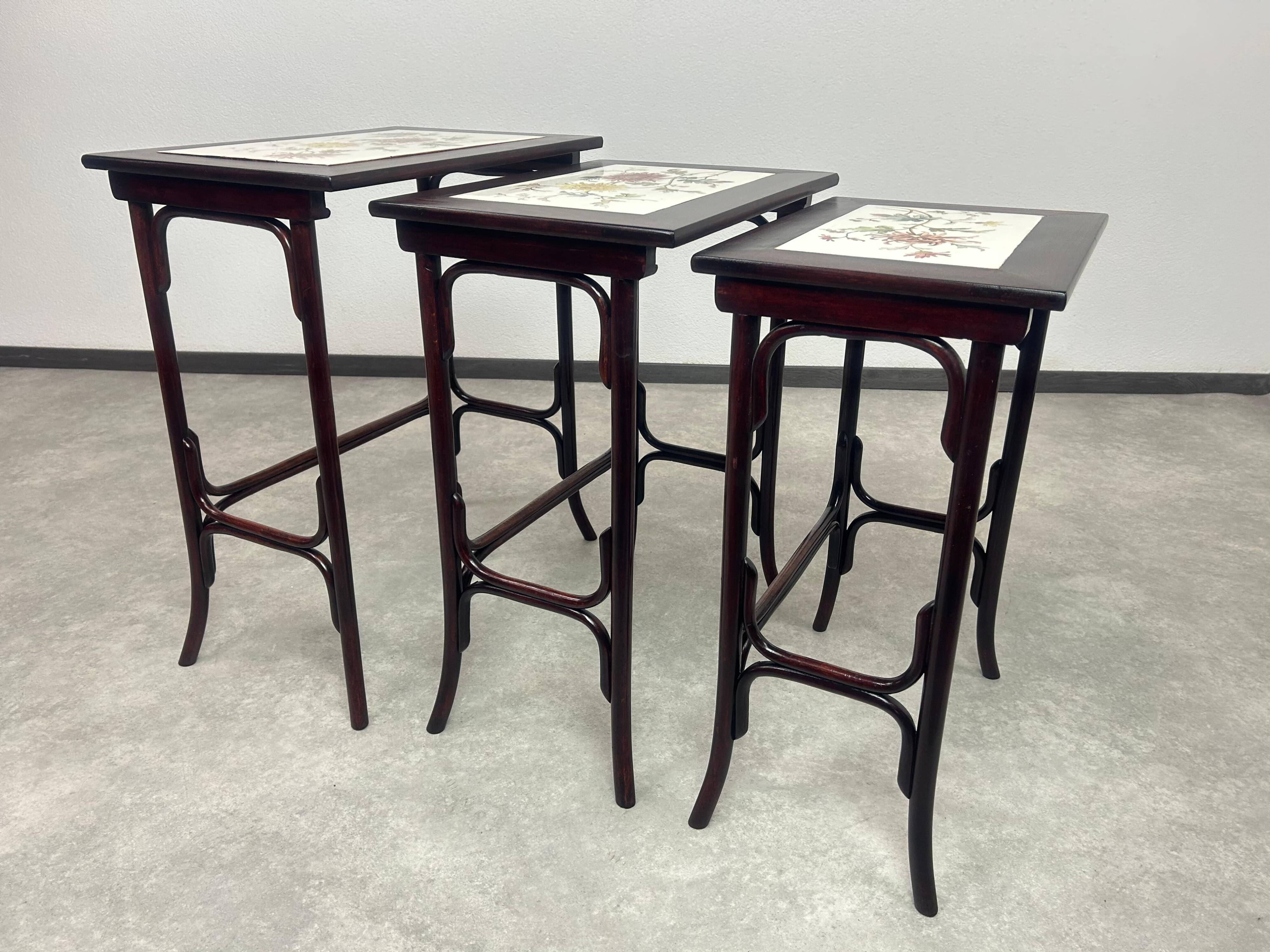 Nested tables in curved wood with ceramic top by Thonet.