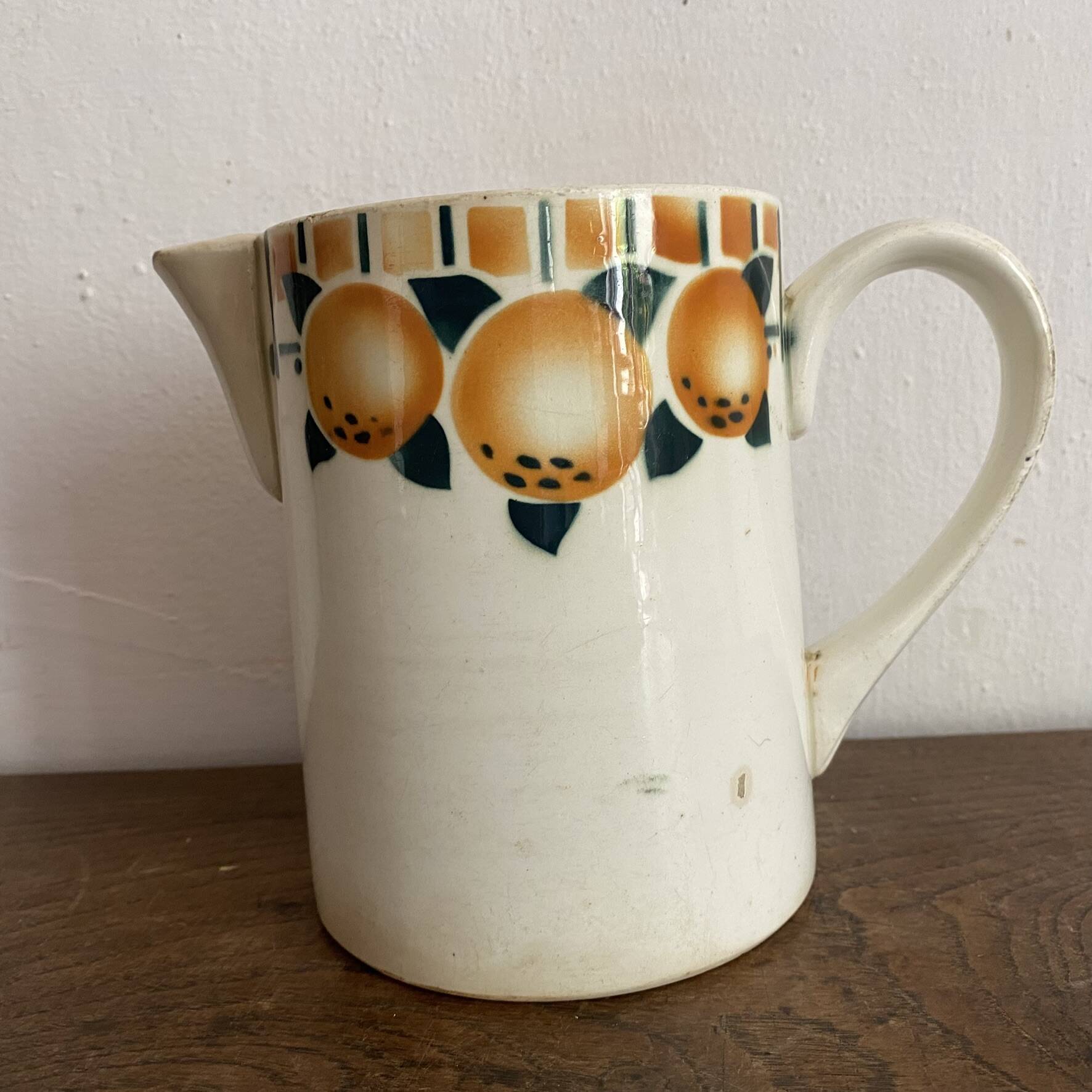 Old ceramic pitcher with orange decoration.