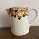 Old ceramic pitcher with orange decoration.
