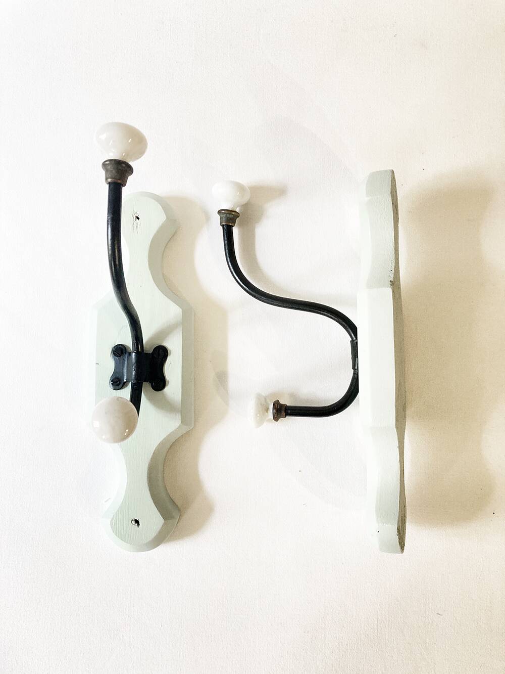Antique metal and porcelain coat hooks, painted wooden support