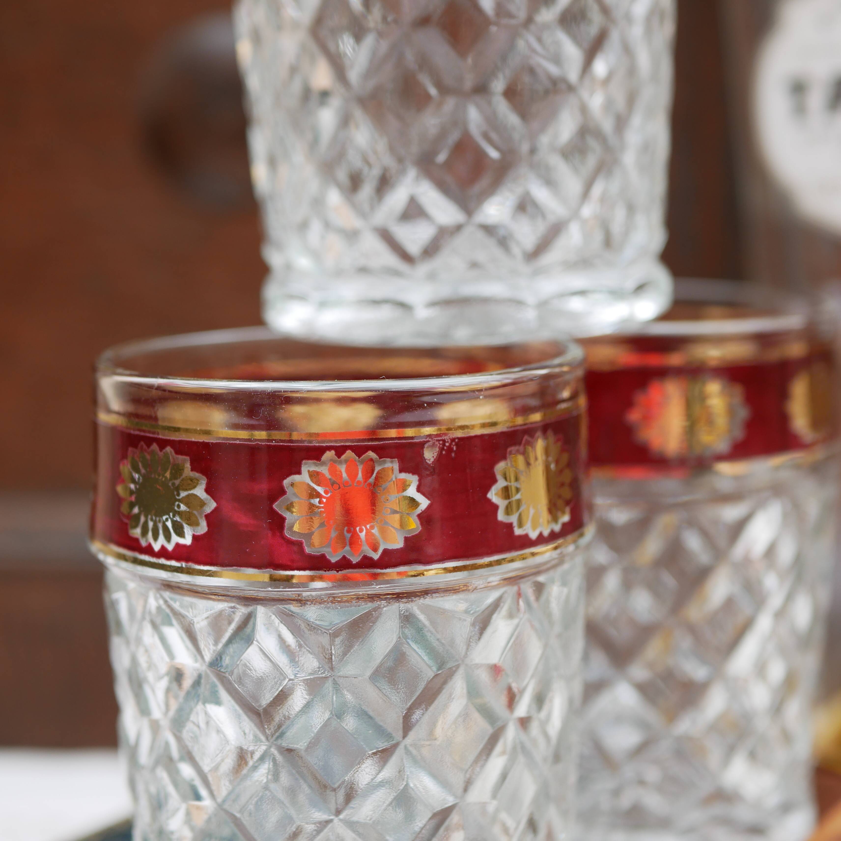 Six pressed glass whisky glasses with red and gold rims