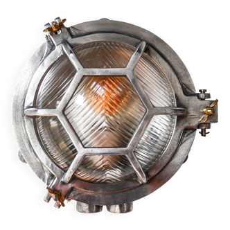 Old cast aluminum wall light with hexagonal grid and wide streaked glass.