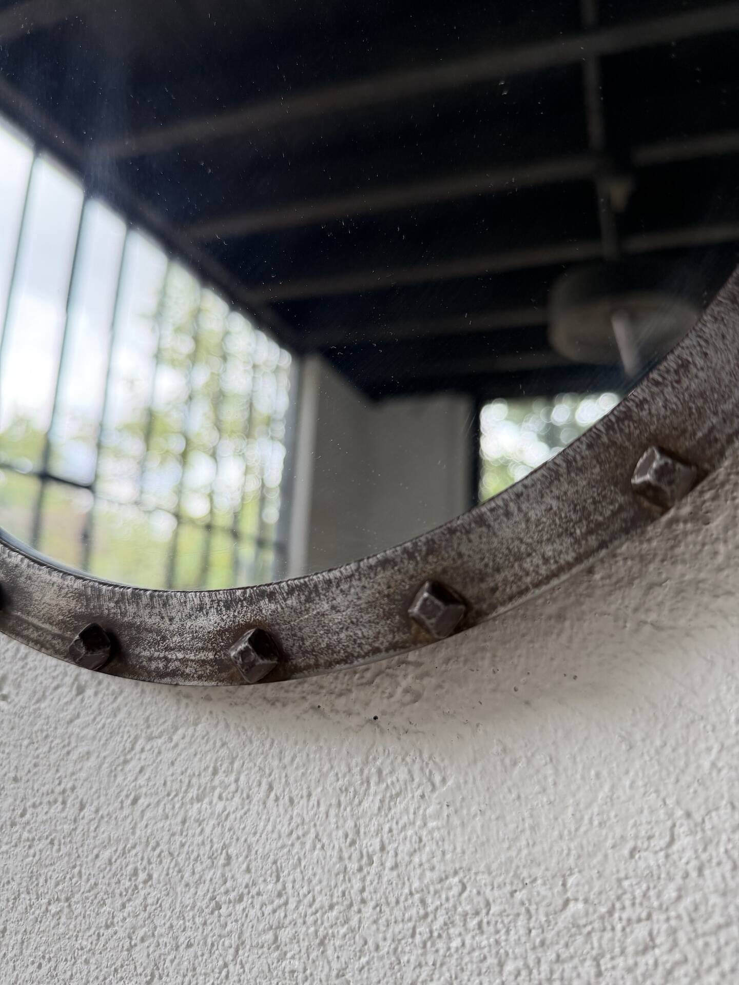 Brutalist round mirror with wrought iron and studs.