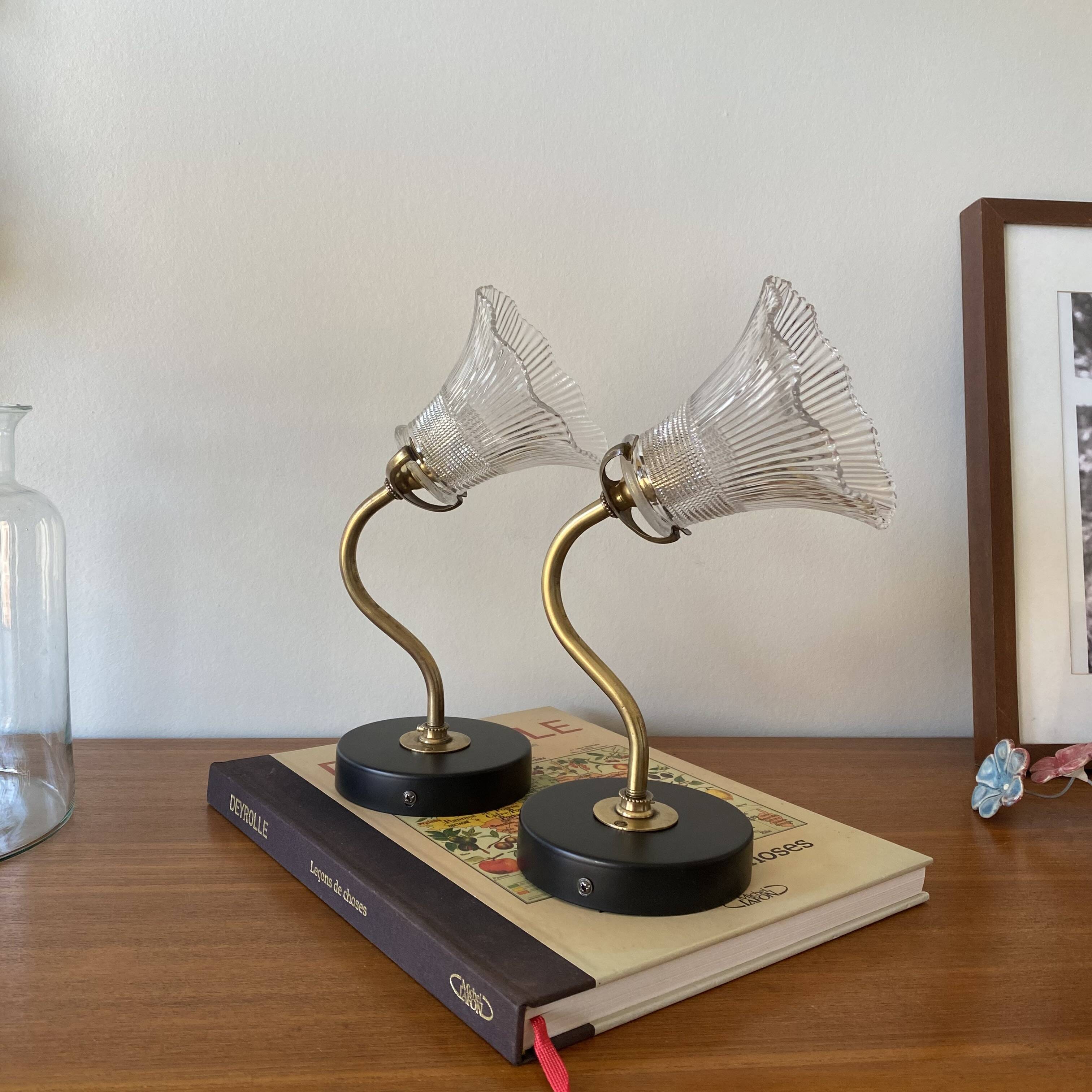 Pair of brass swan neck wall lights with transparent glass shades.