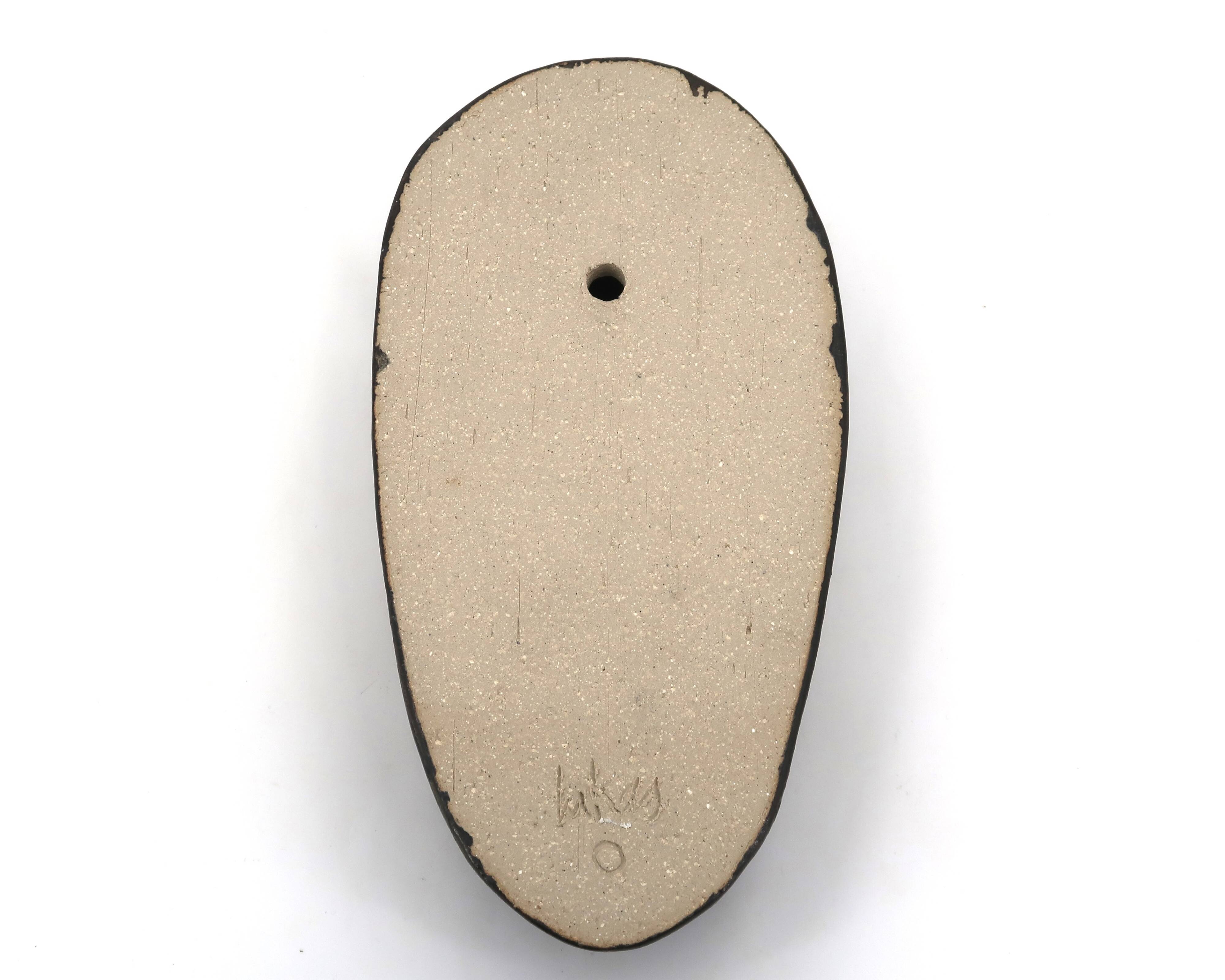 Wall sculpture, stylised mask signed in ceramic.