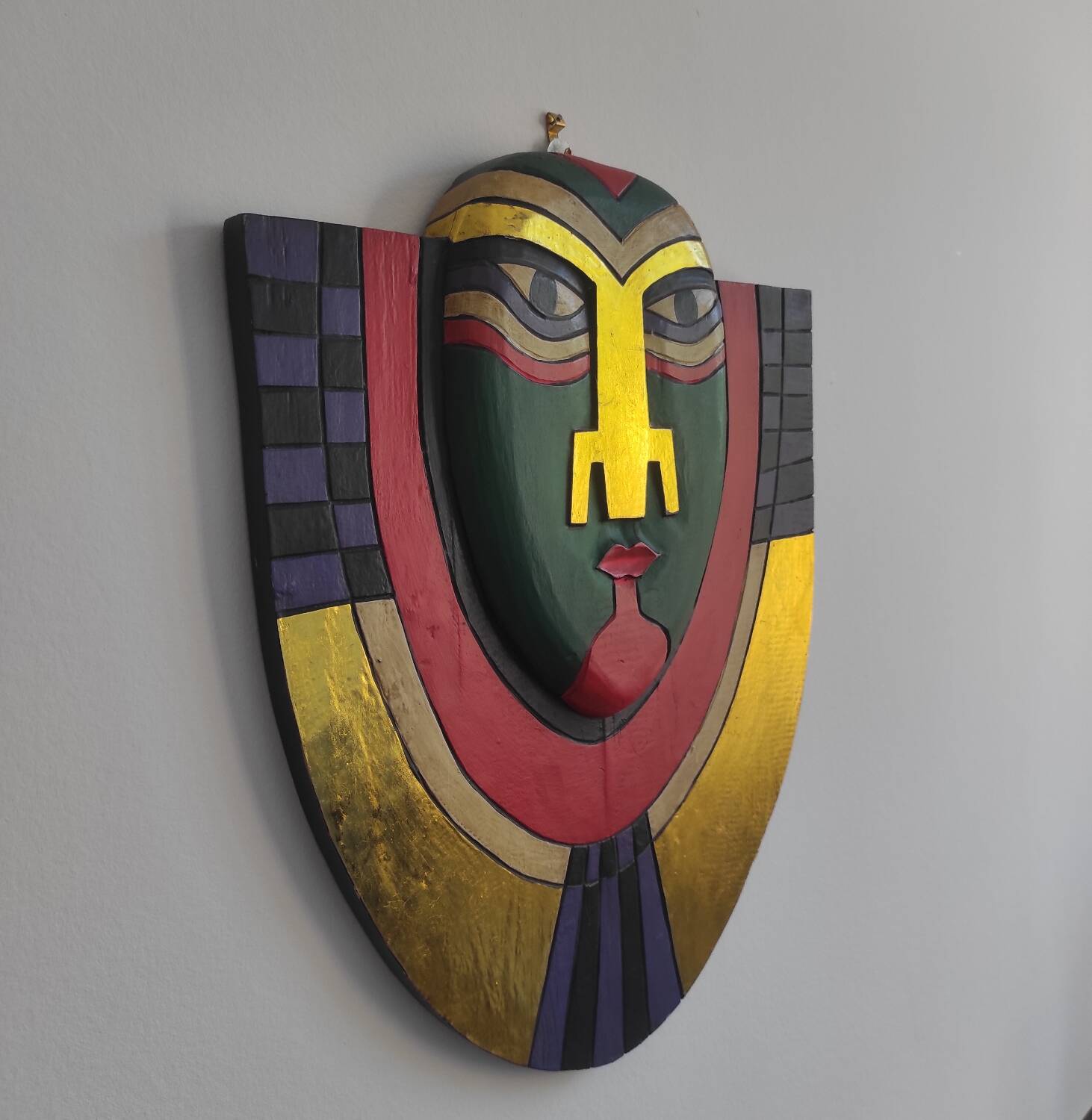 Handcrafted decorative wall mask made of painted wood.