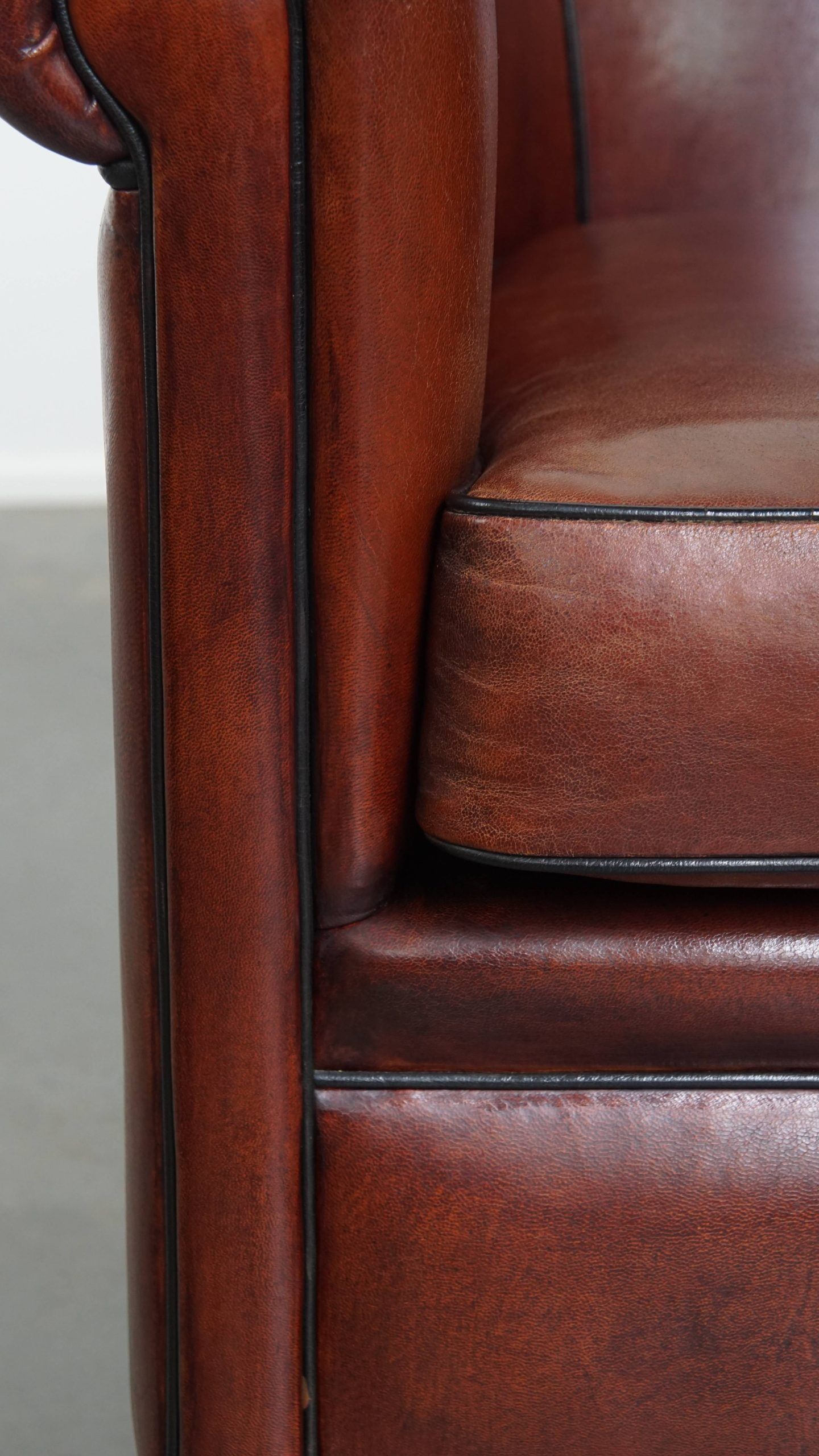 Sheepskin club armchair in a warm deep colour finished with black piping