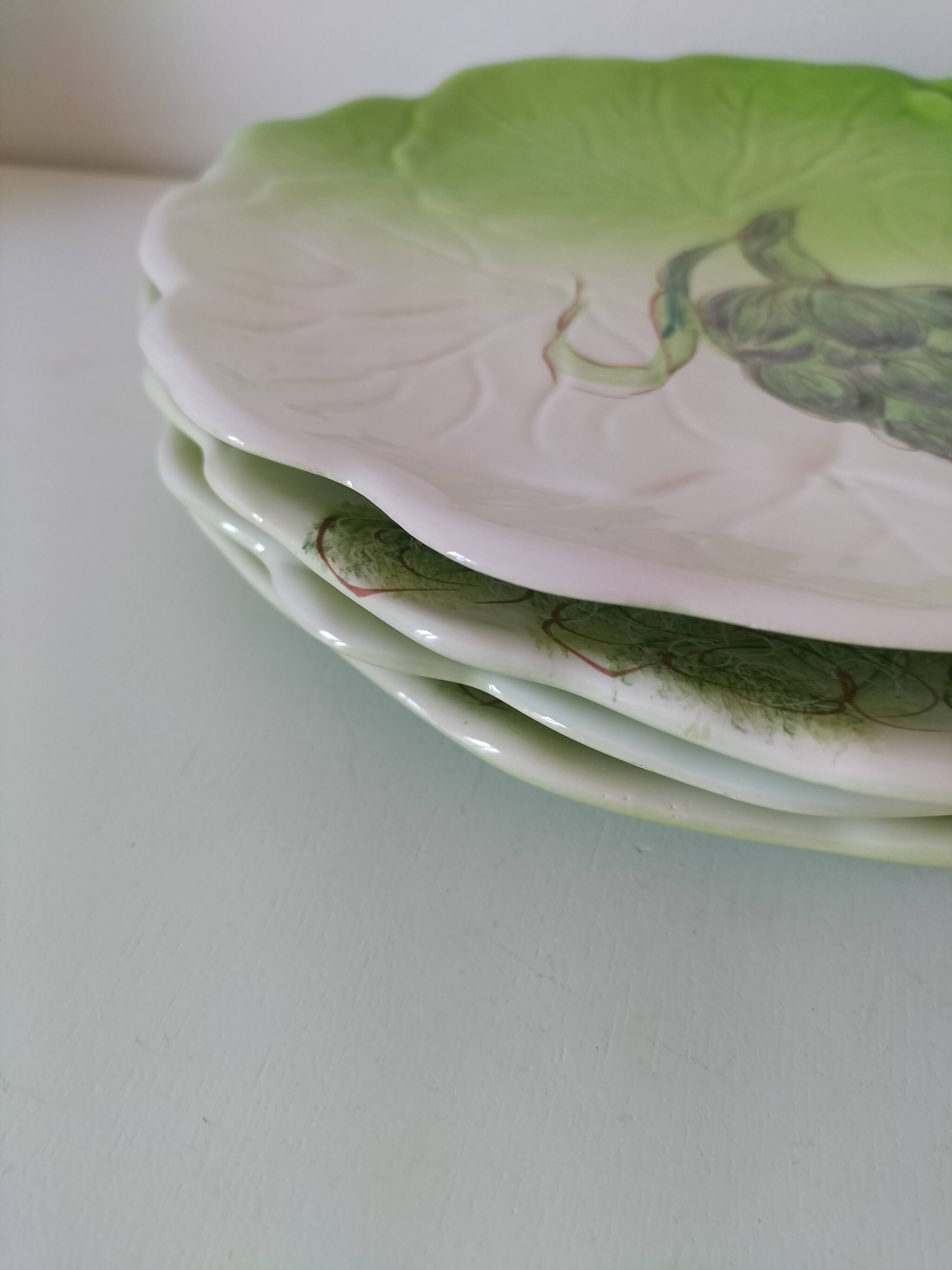 4 hand-decorated earthenware plates with vegetable and green leaf designs.