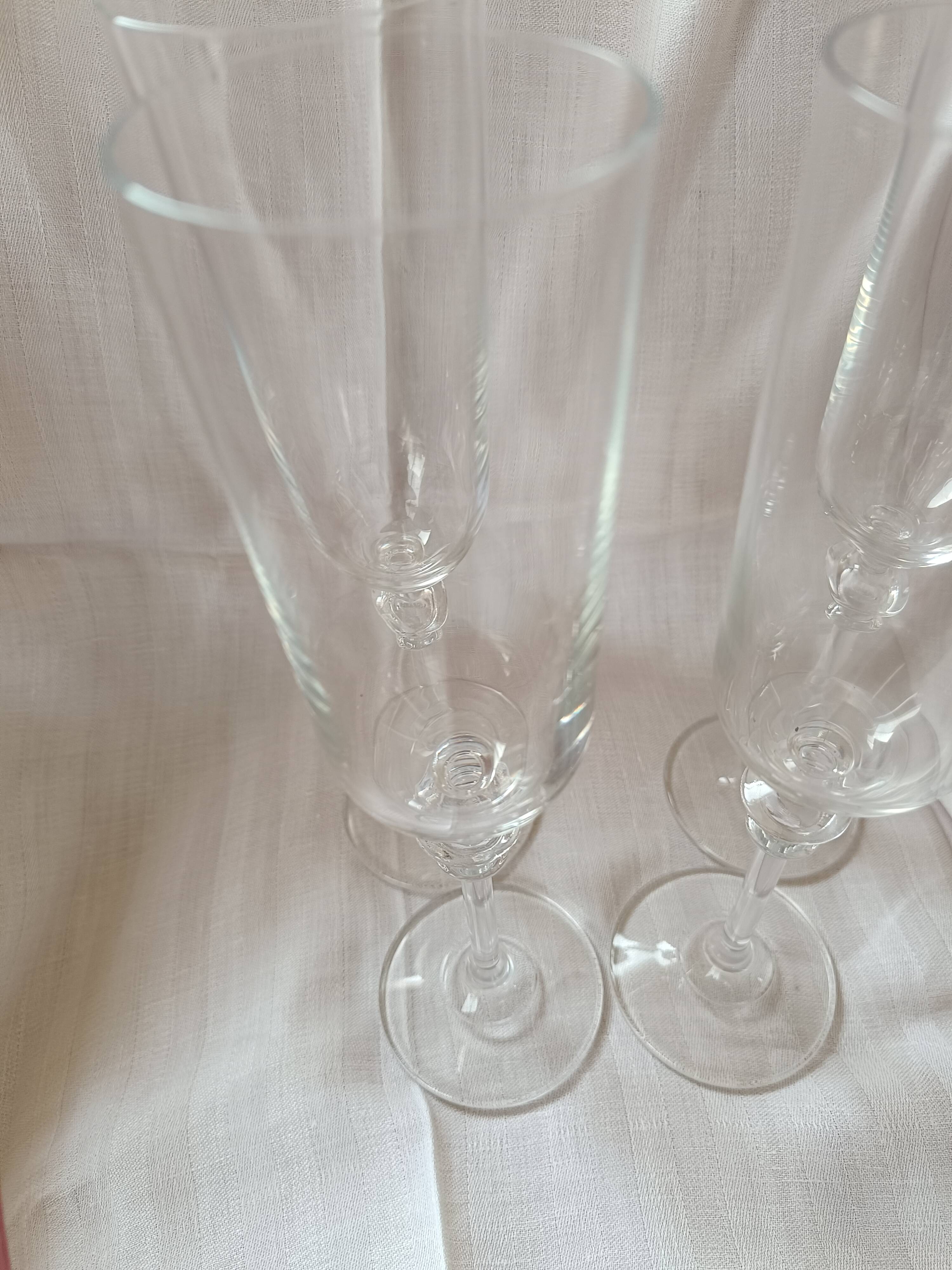 4 crystal champagne flutes with feet decorated with two knots.