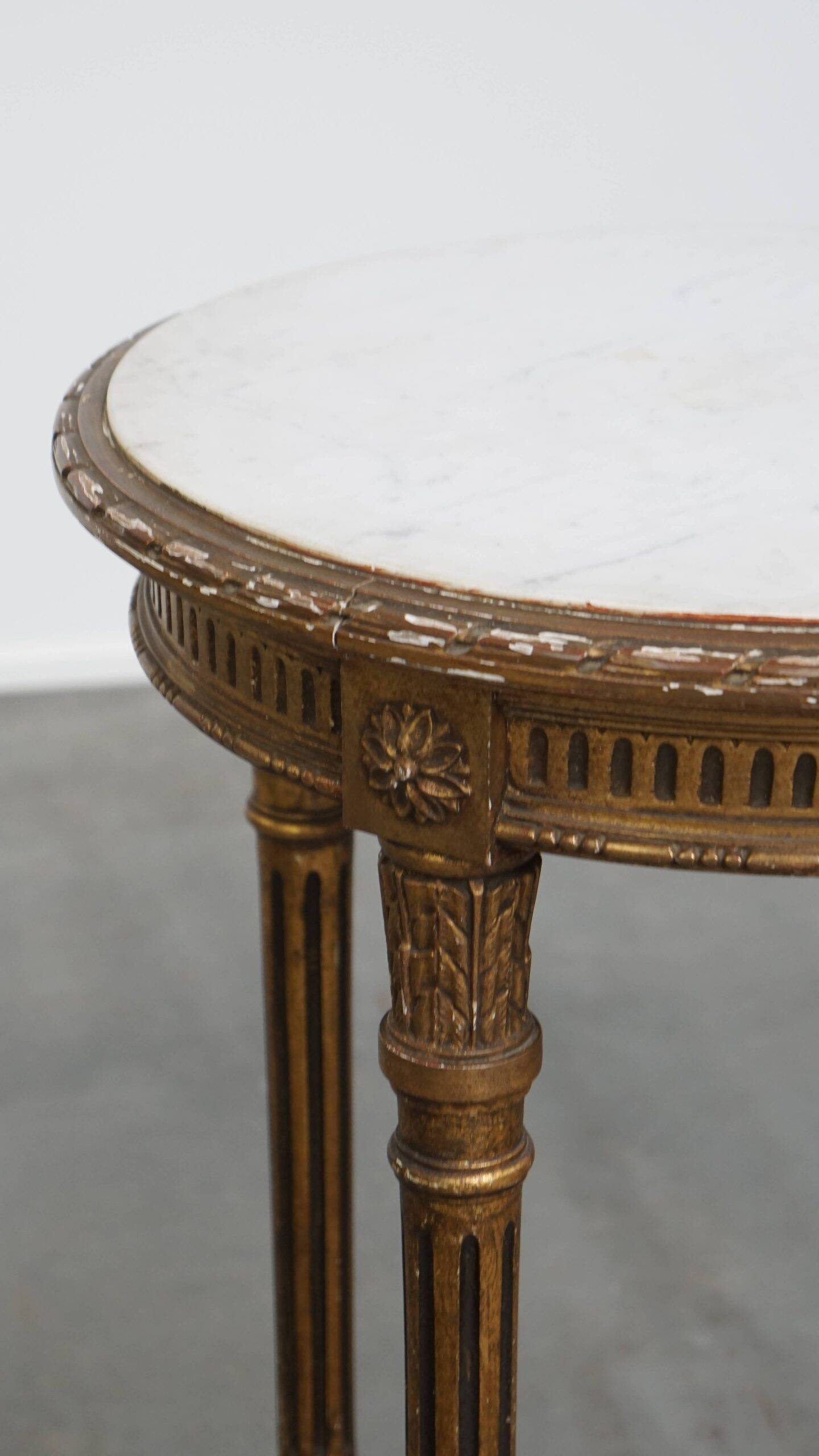 Antique French round side table in golden colour with a marble top.