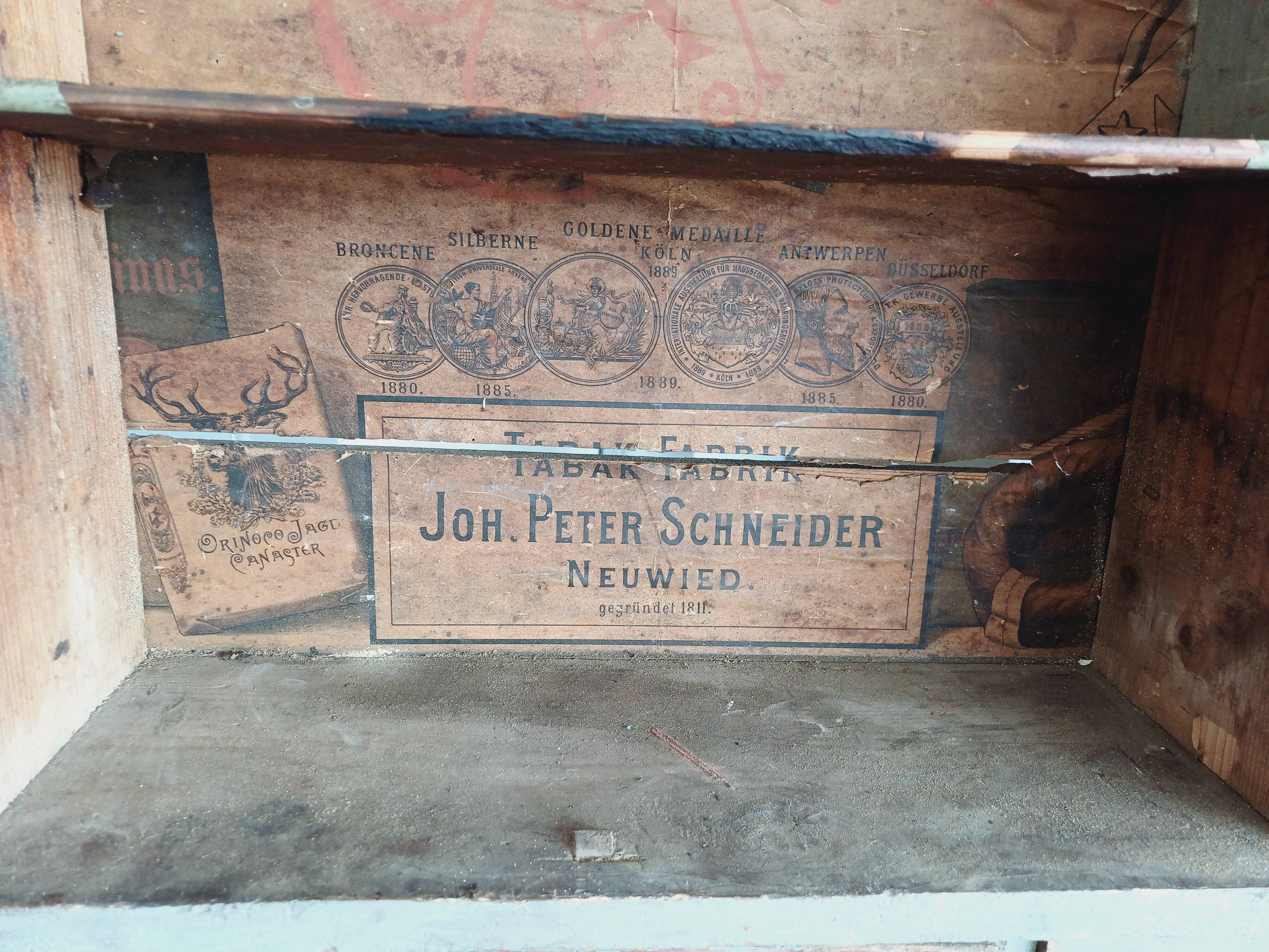 Craft cabinet with drawers with a very old tobacco advertisement in the background
