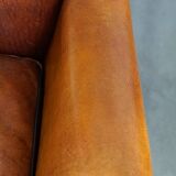 Subtle sheepskin wing chair in good condition on brass front wheels