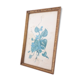 Decorative table with vintage blue flowers in a golden frame.